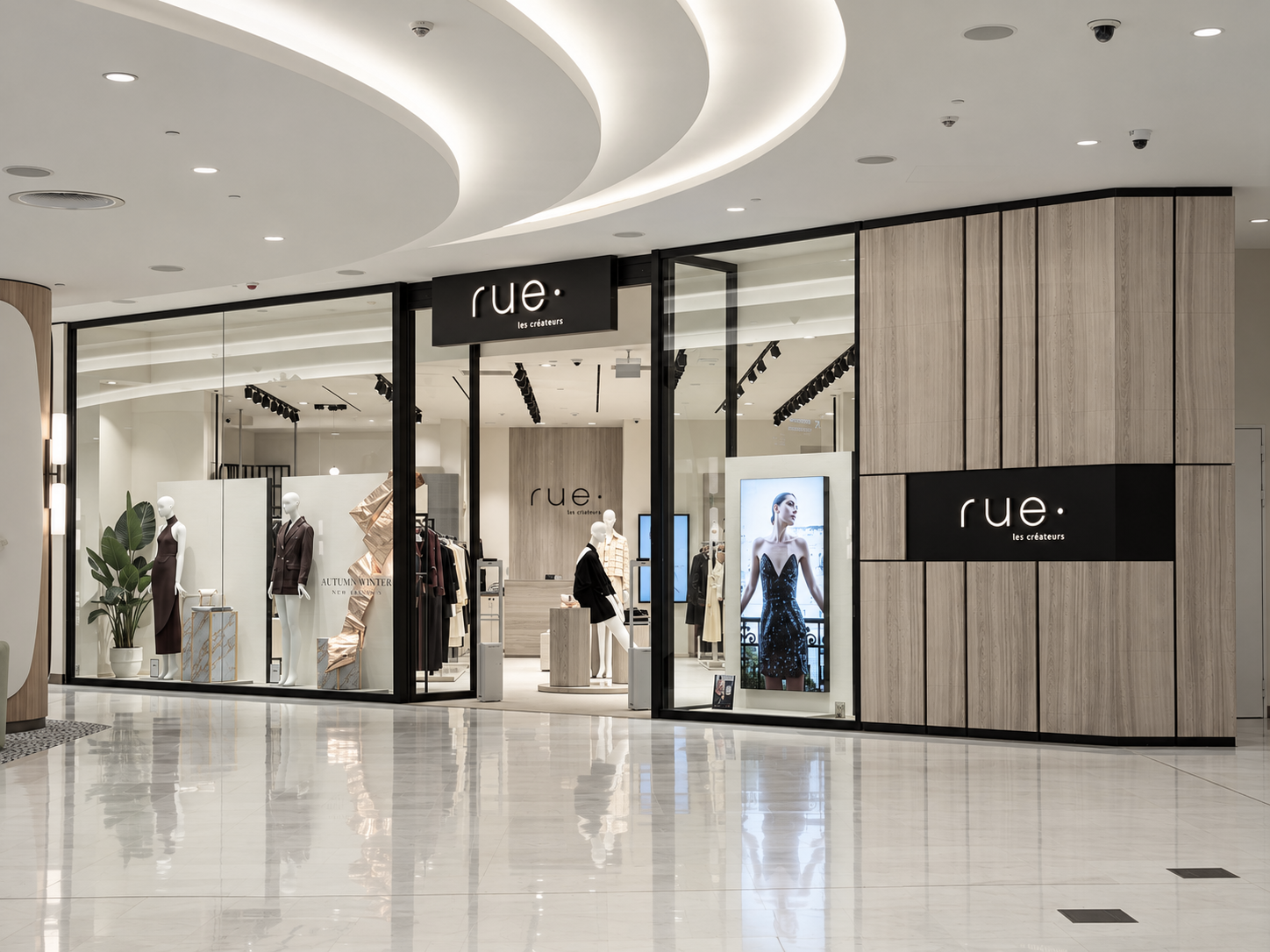 Clothing store named Rue with mannequins displaying dresses and suits, digital signage of a woman in a dress, and a modern interior with wooden panels and white ceiling