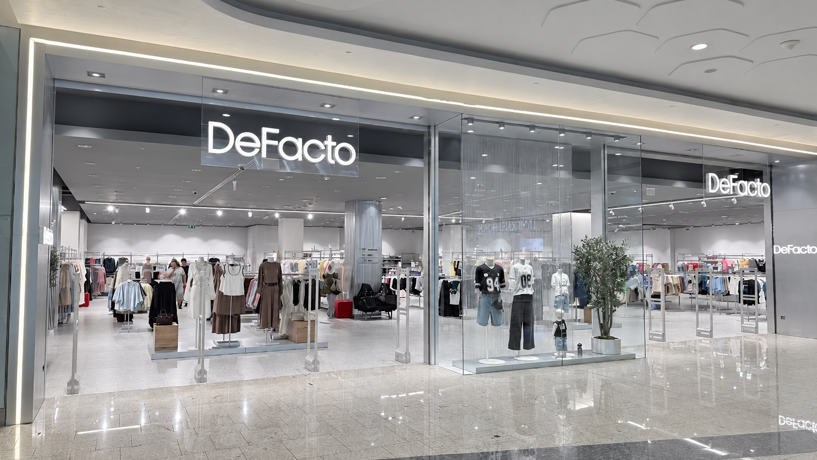 Front view of the DeFacto clothing store in a mall, with mannequins and clothing displays inside.