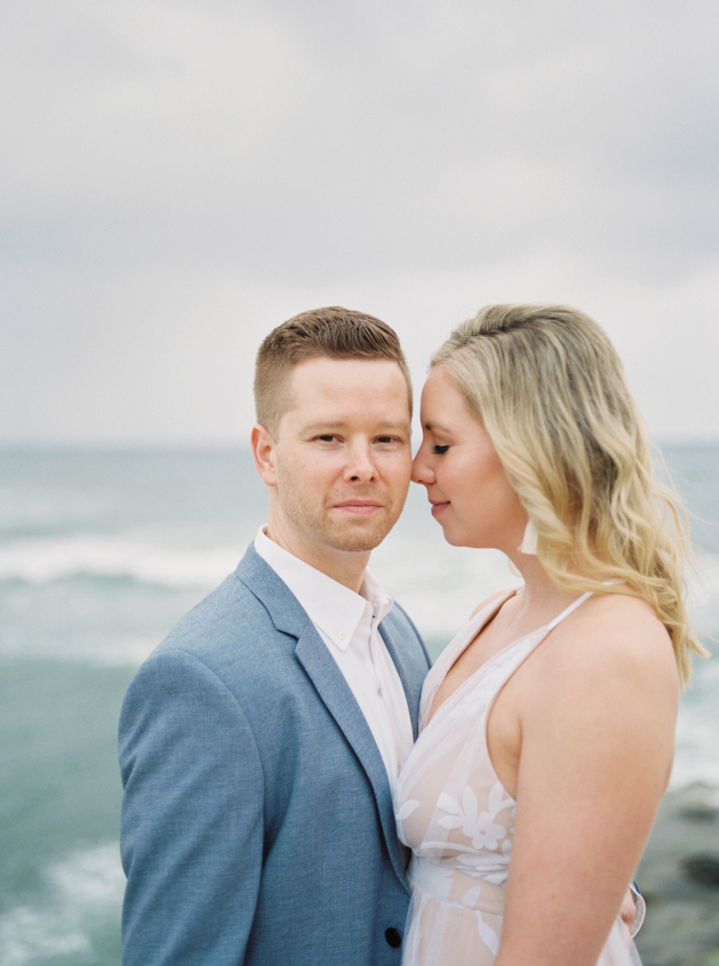 Anniversary wedding session on film at the Sunset Cliffs in San Diego California with stylish white flowy dress and blue suit by the ocean and beach by Liz Andolina Photography