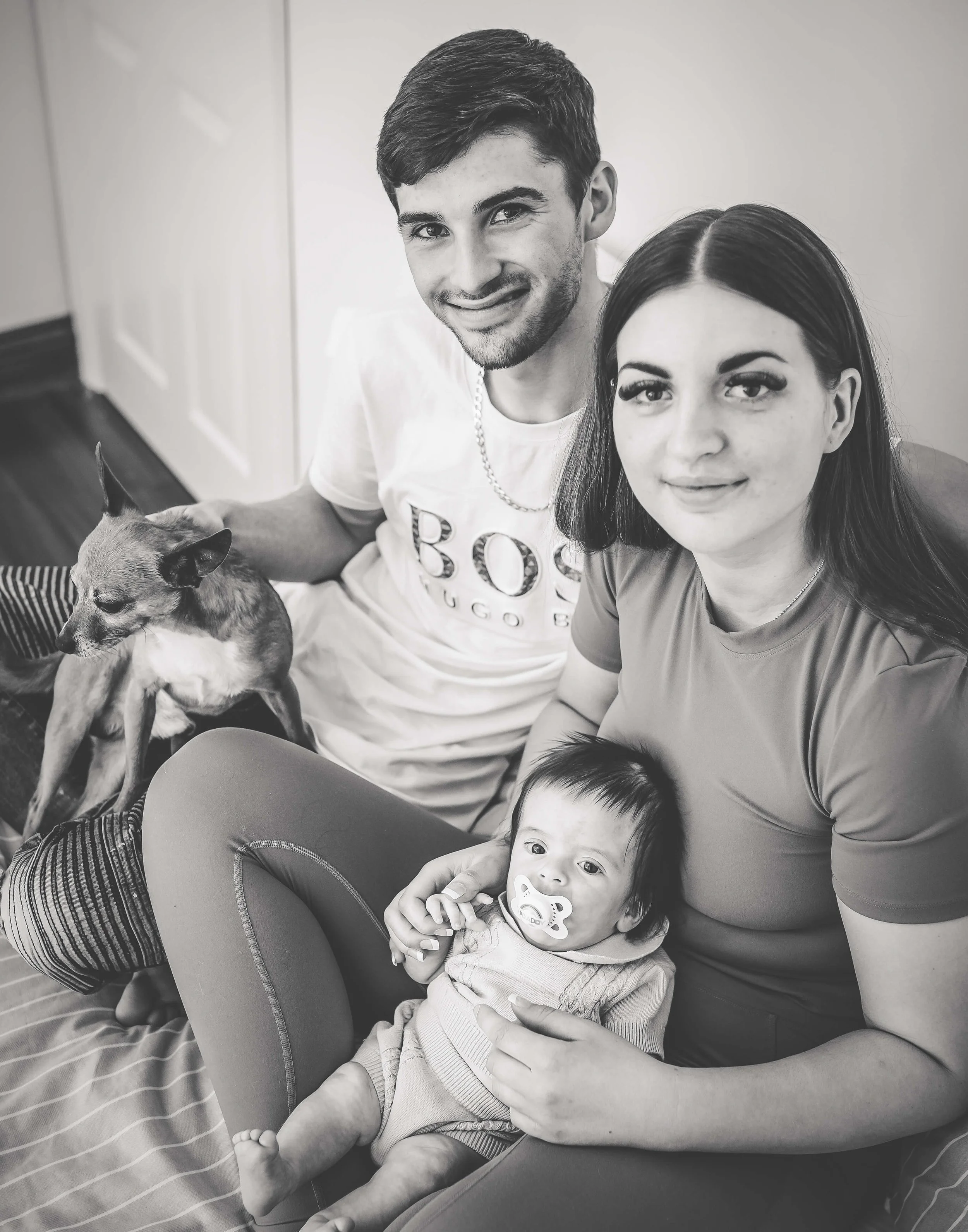 mum and dad on bed with baby and their little dog 