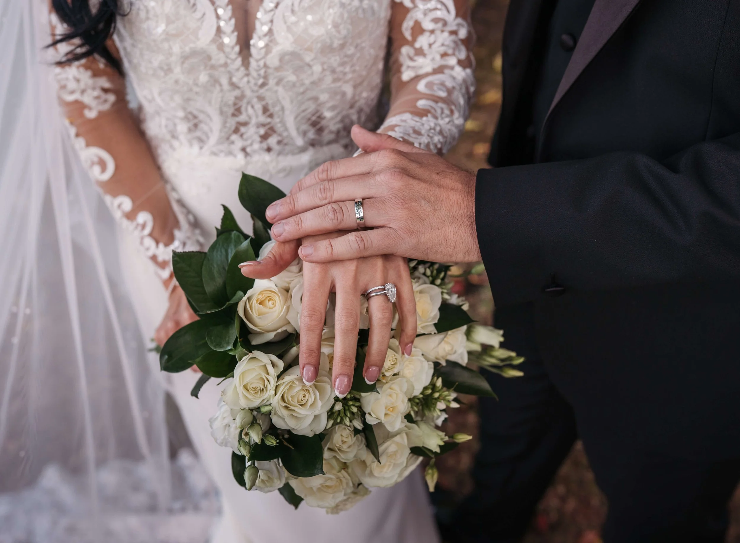 above shot of bride and grooms hands and bouquet showing off their gorgeous wedding rings 