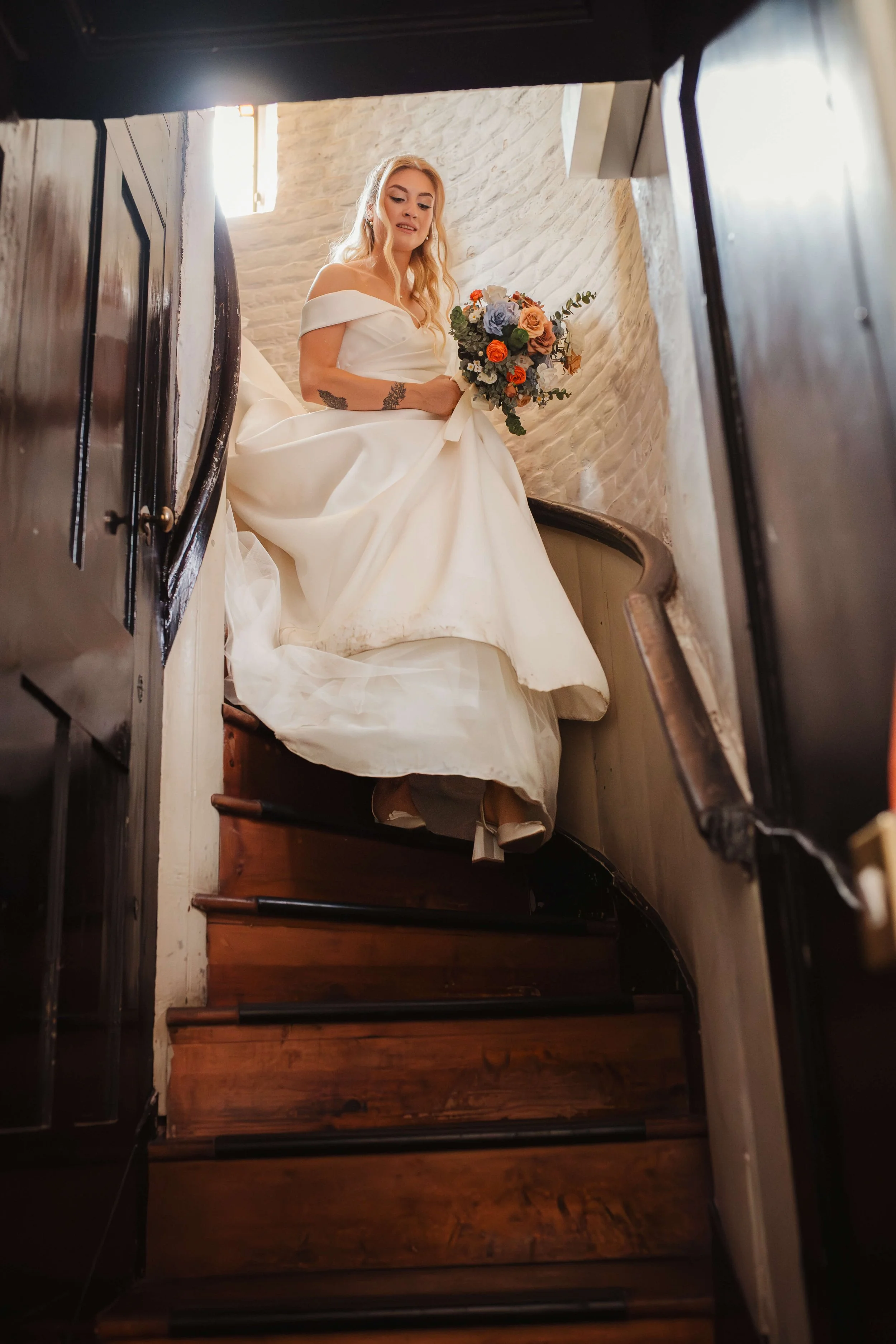 bride descends staircase holding her bouquet 