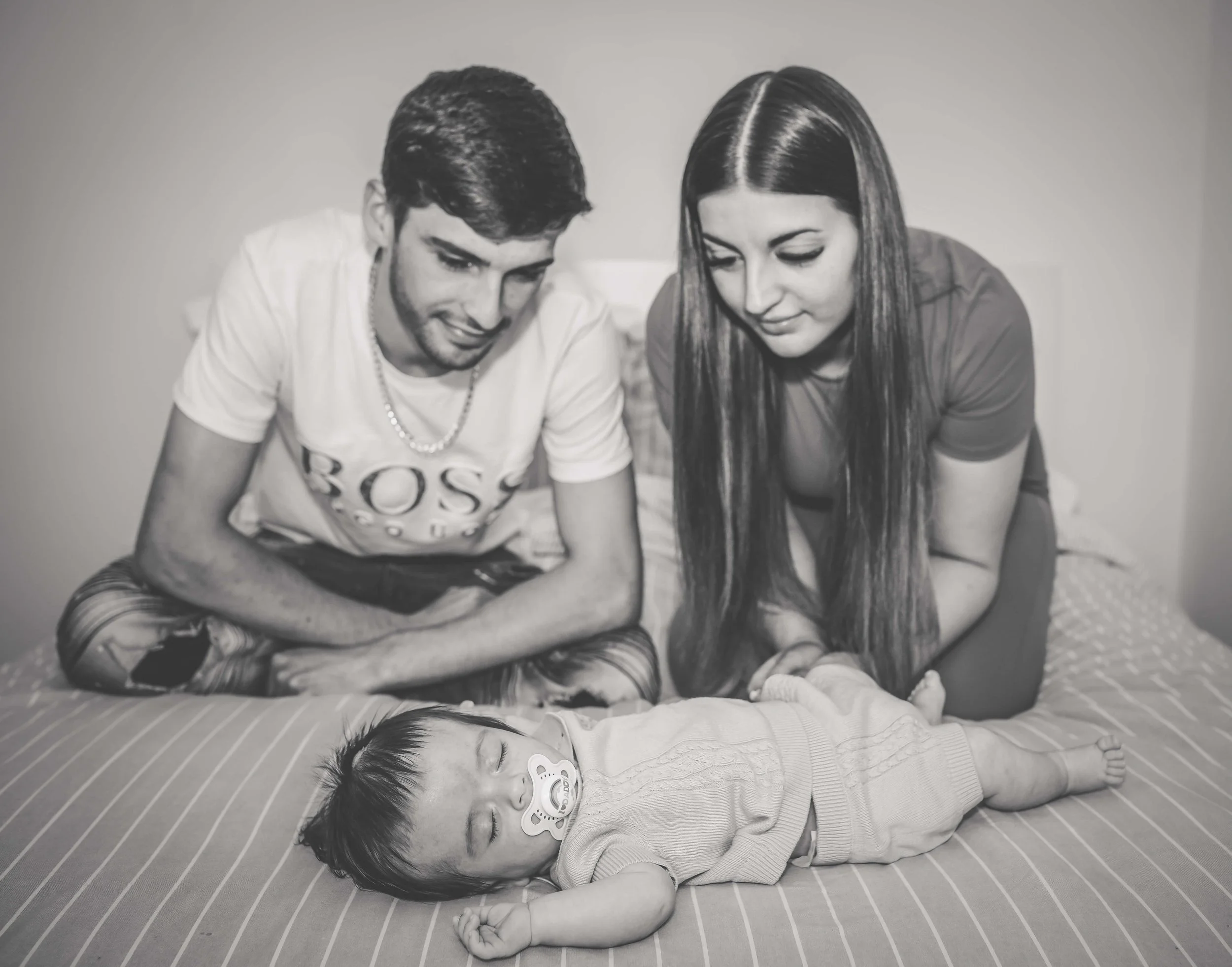 mum and dad looking on lovingly as baby sleeps 