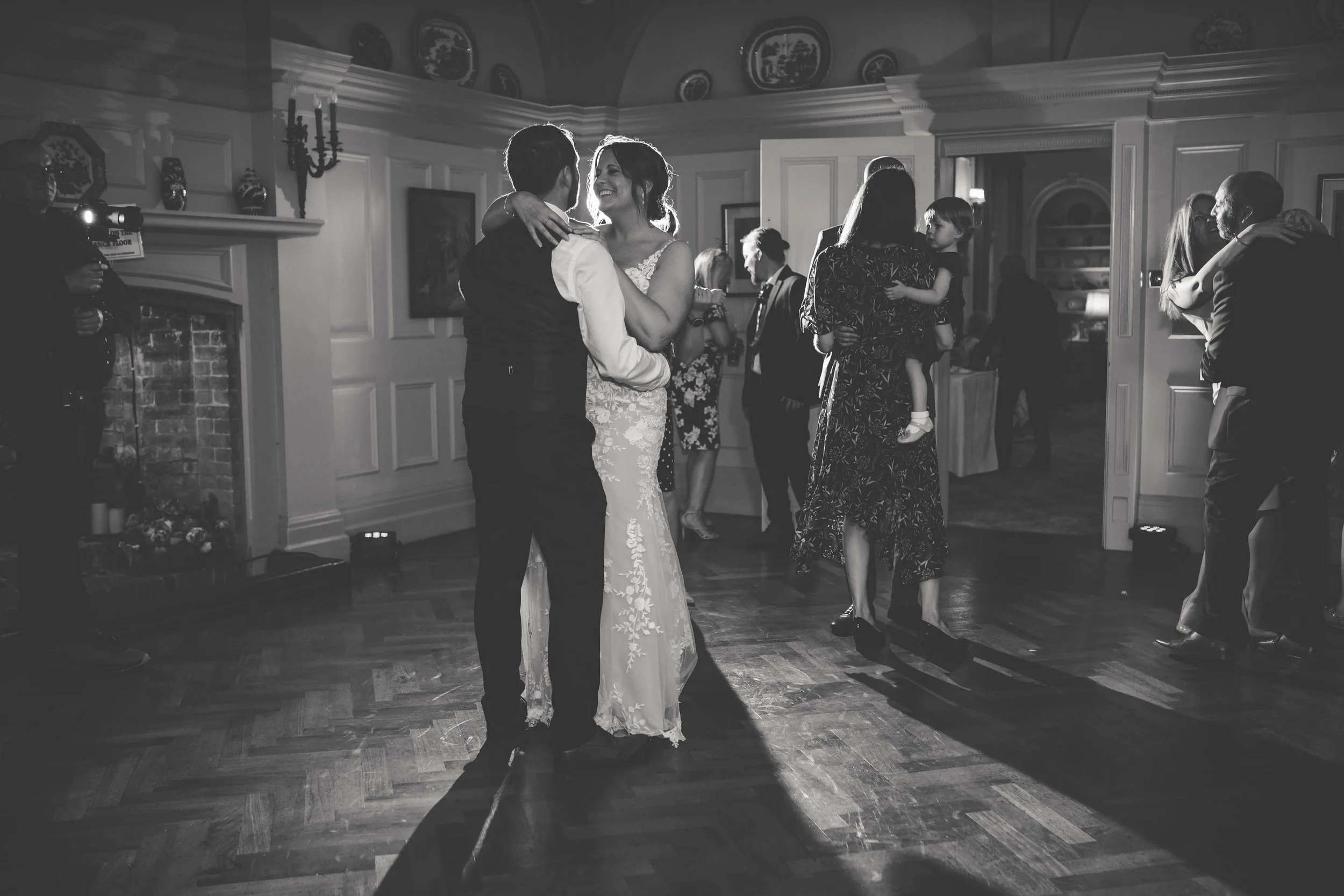 A black-and-white photo of a wedding reception dance floor with couples dancing and a bride and groom dancing together in the center.
