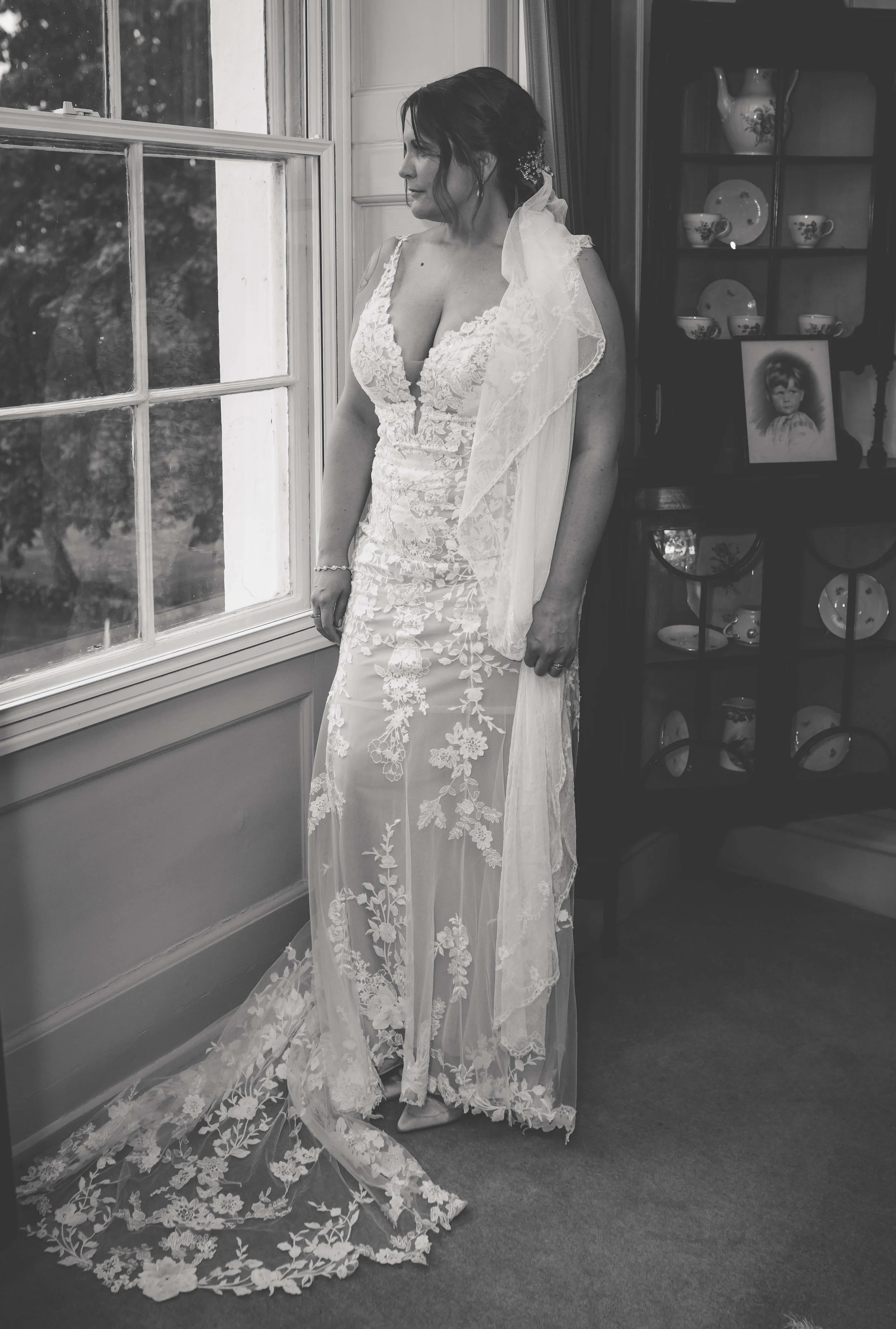 A woman in a wedding gown looking out a window.