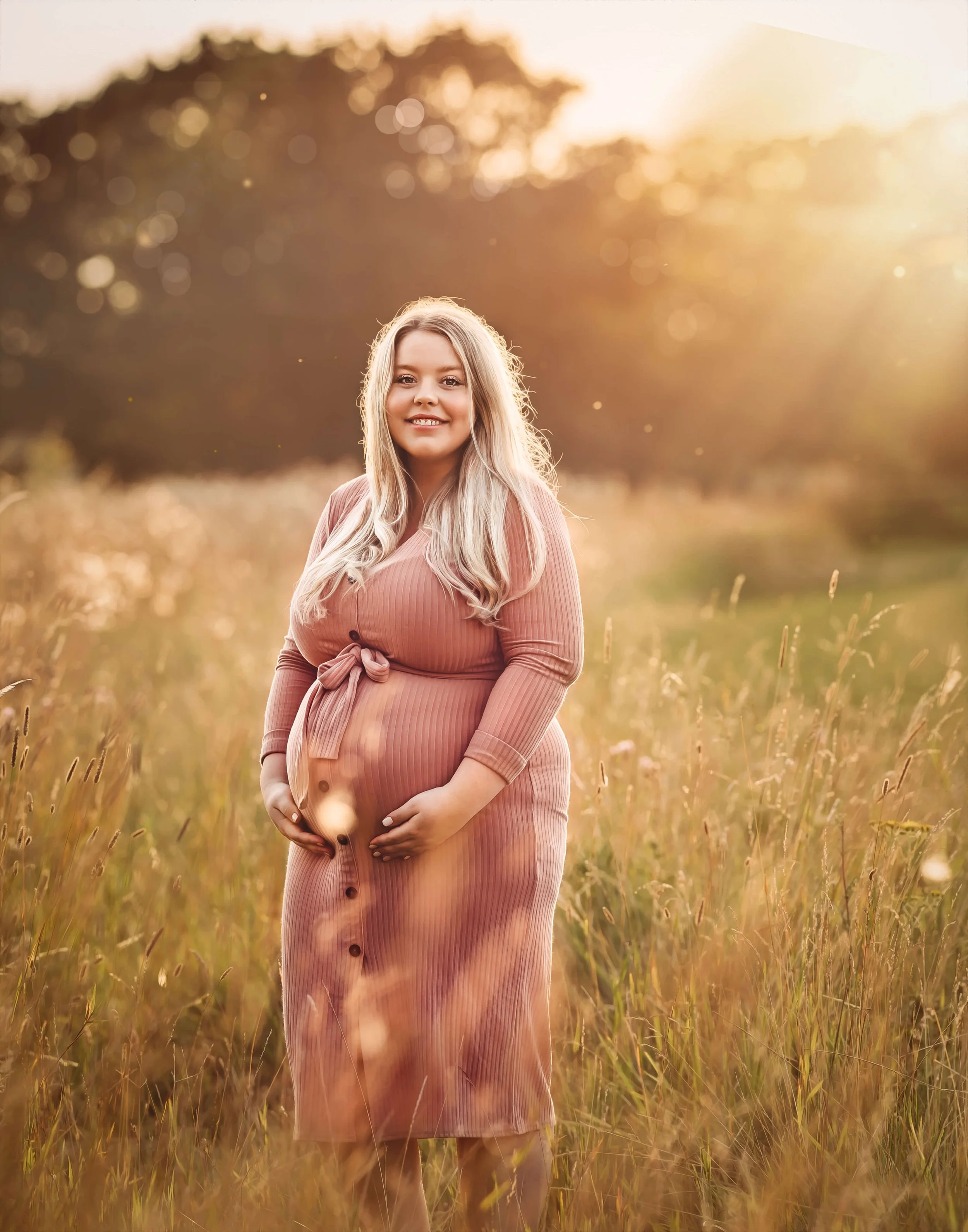 maternity shot of mum to be in tall grass field at golden hour 