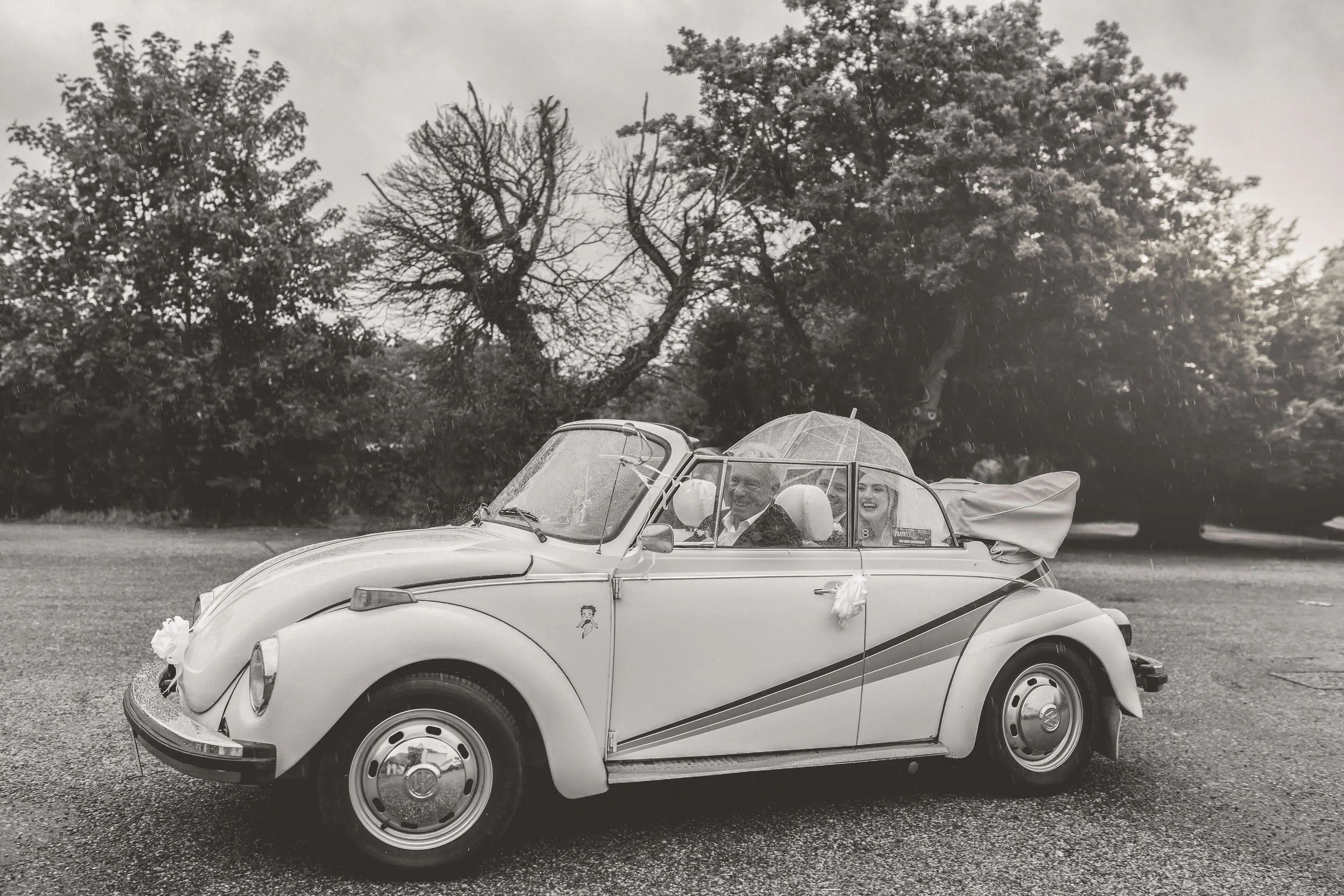 bride and groom arriving to The Willow Room for their reception in their vw beetle convertible
