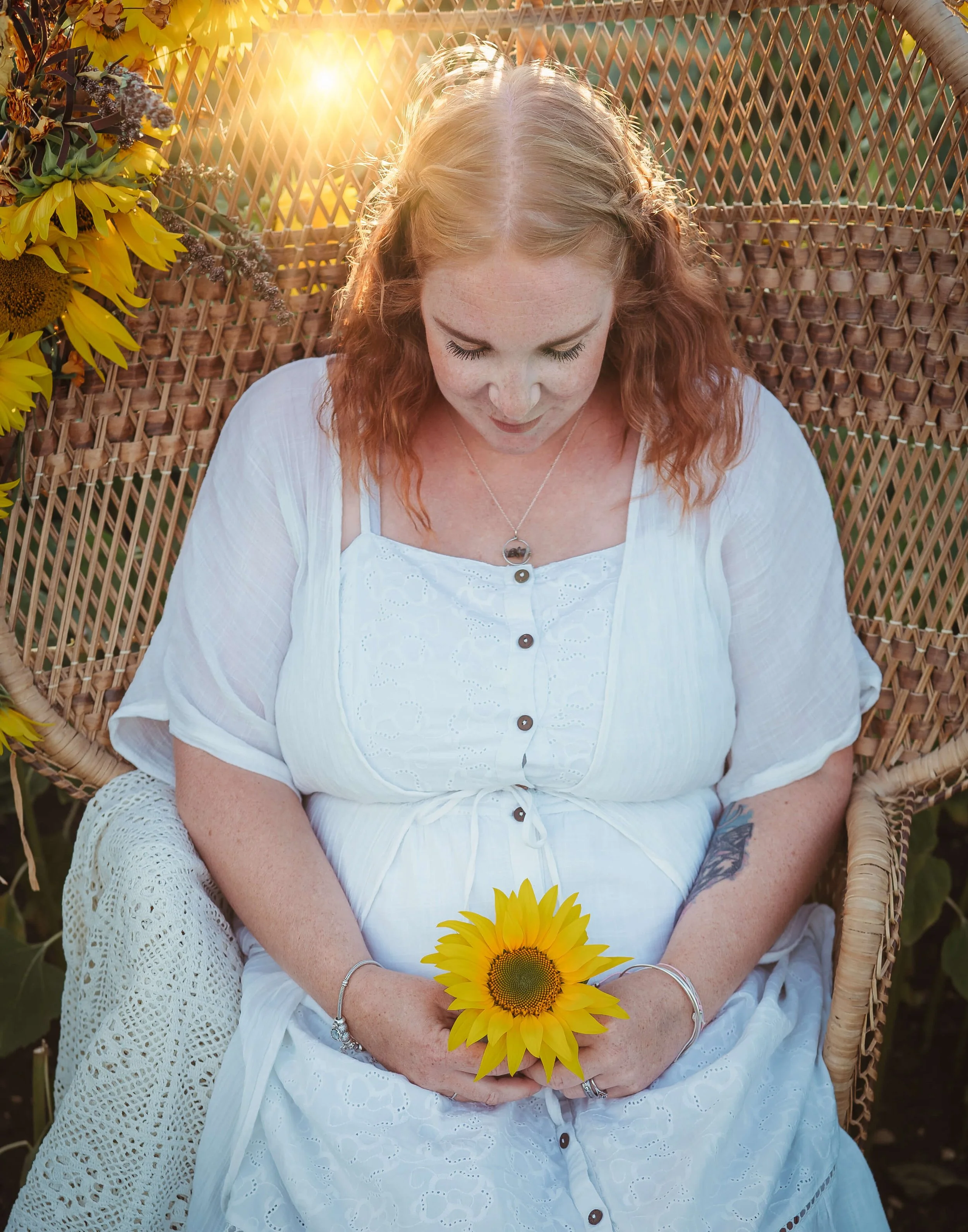 mum looks down at her pregnant belly holding sunflower 