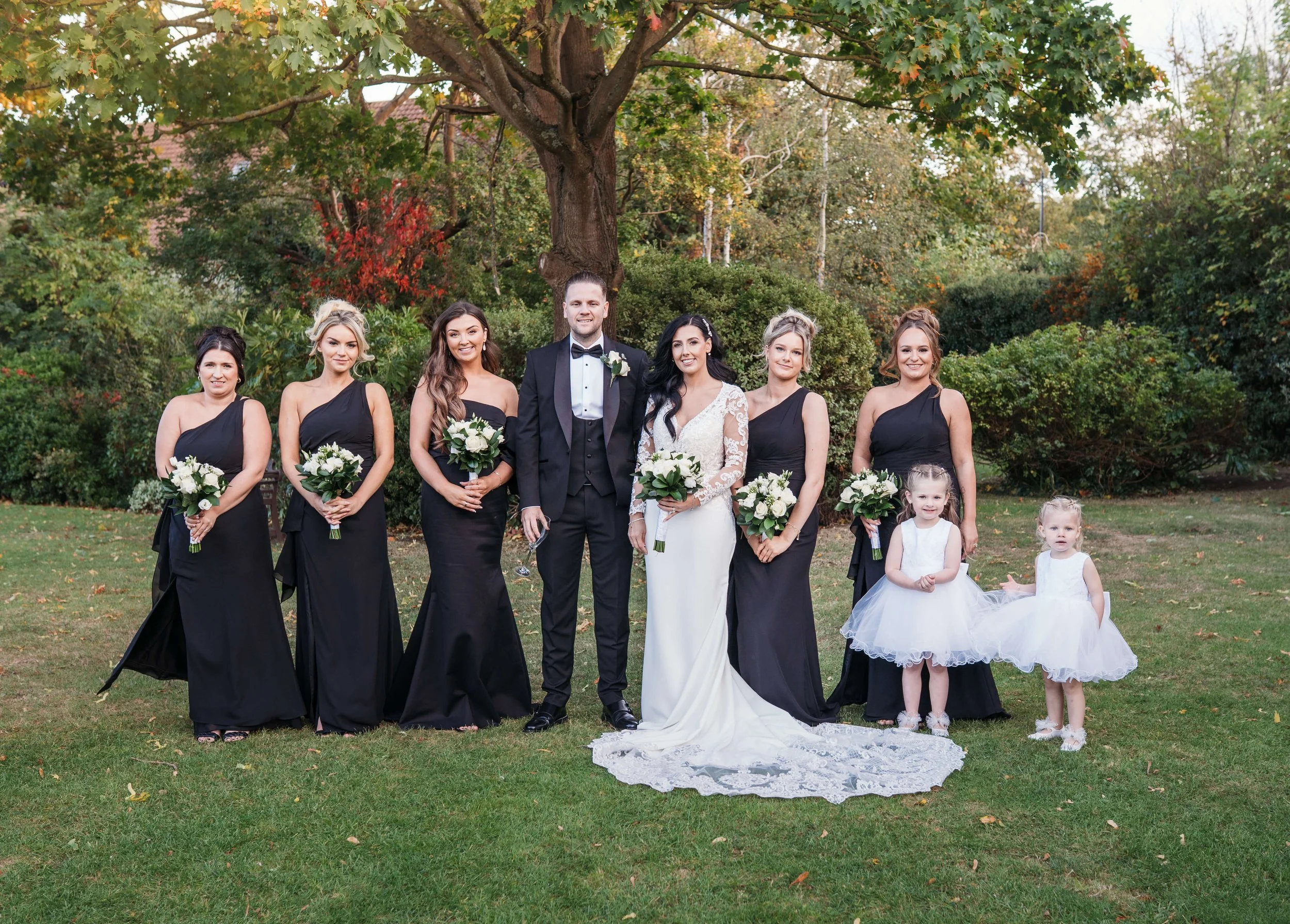 bride and groom with bridesmaids group shot within the Rochford hotel essex grounds 