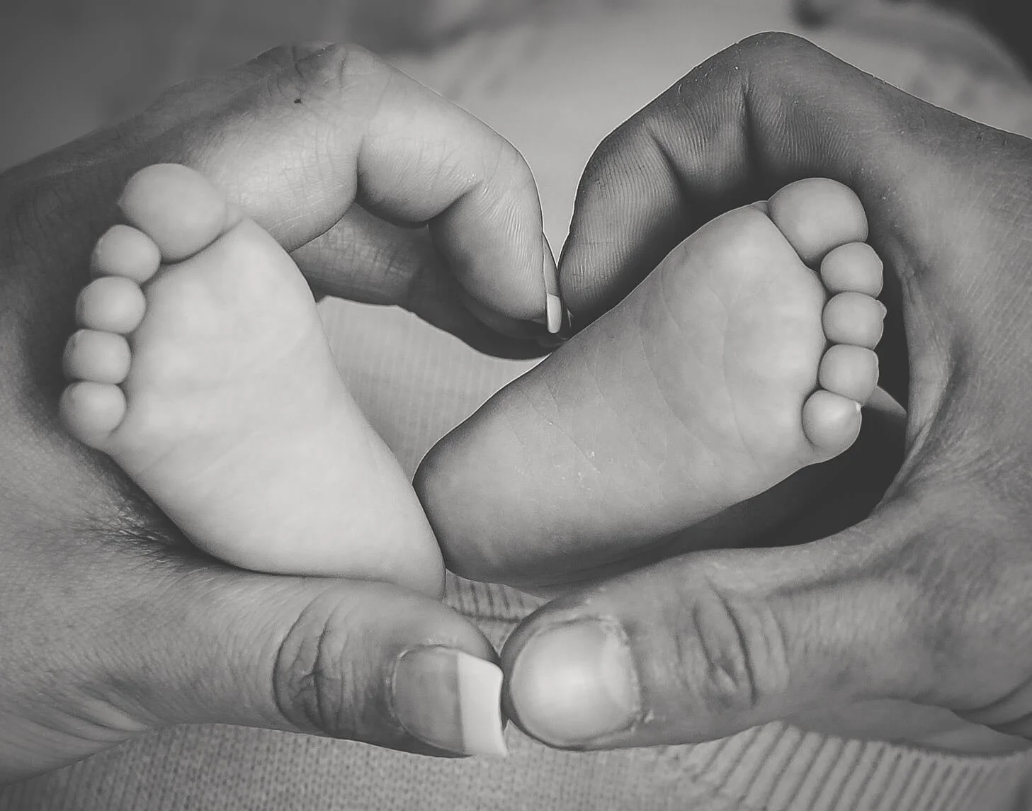 mum and dads hands around baby's feet in shape of a heart 