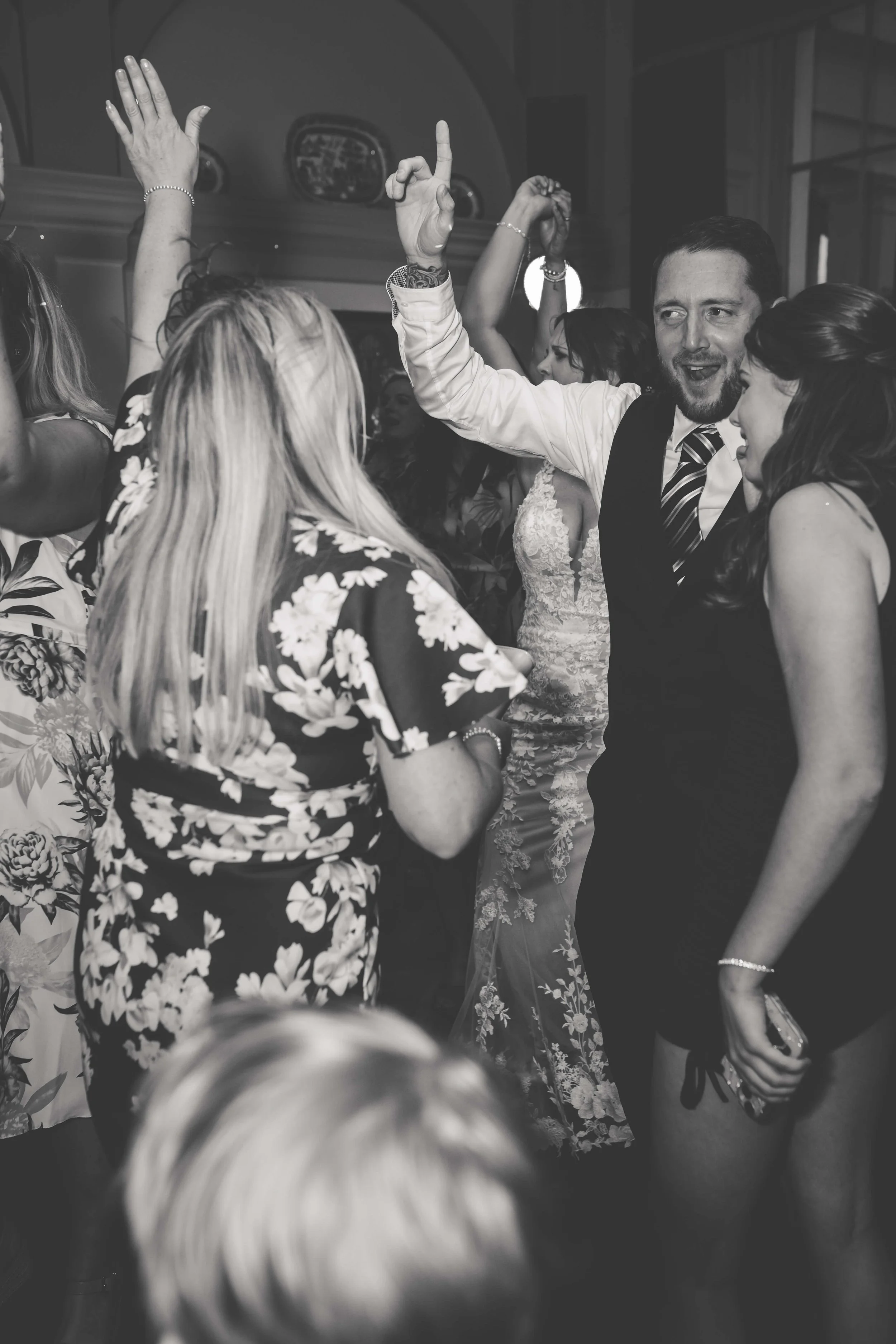 People dancing and celebrating at a party, some with raised hands, in a lively indoor setting.