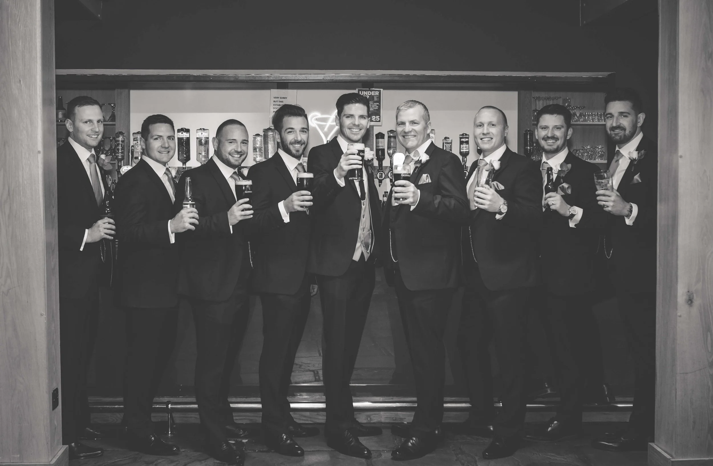 groomsmen all share a pint together in a posed photograph