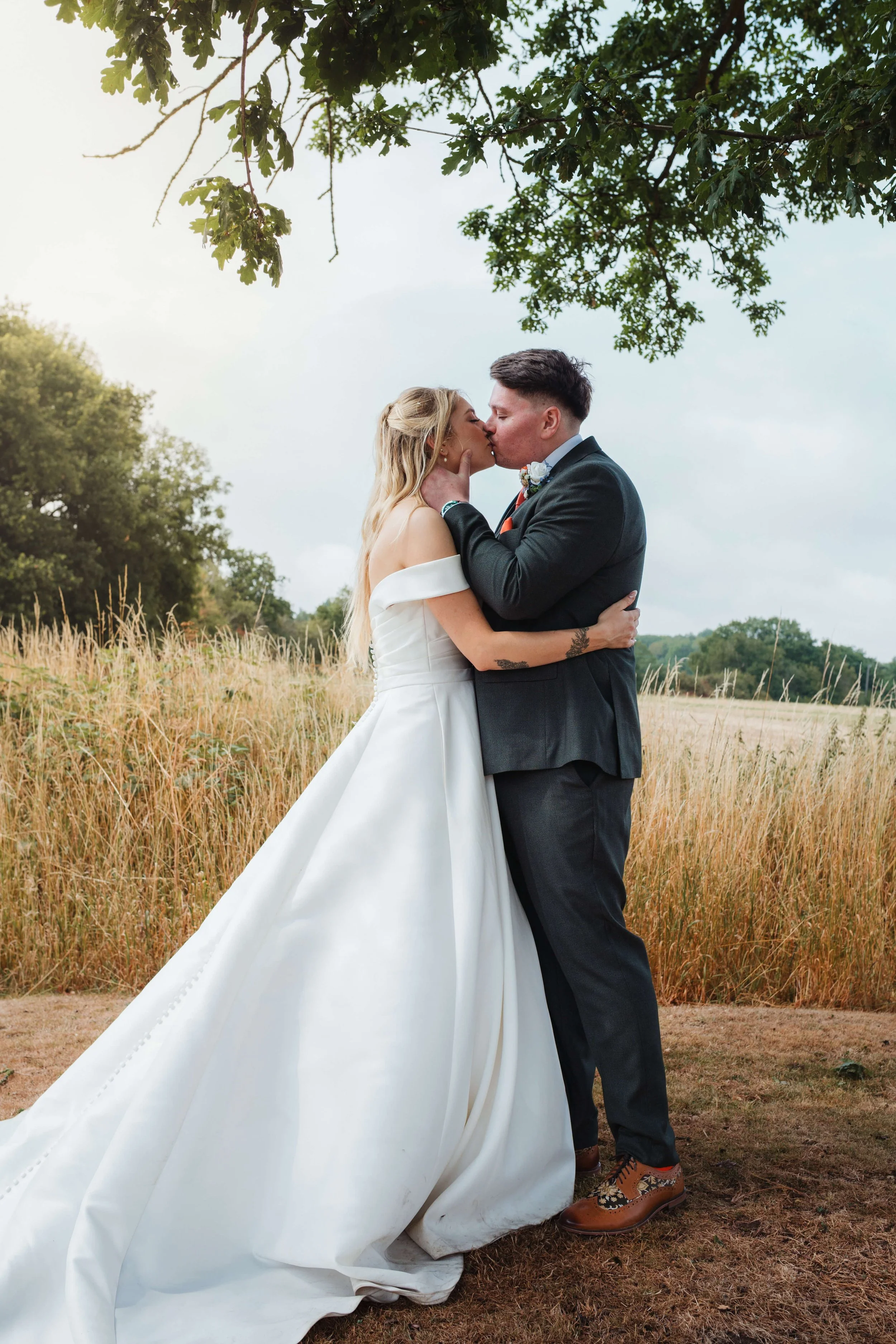 bride and groom share passionate kiss under tree