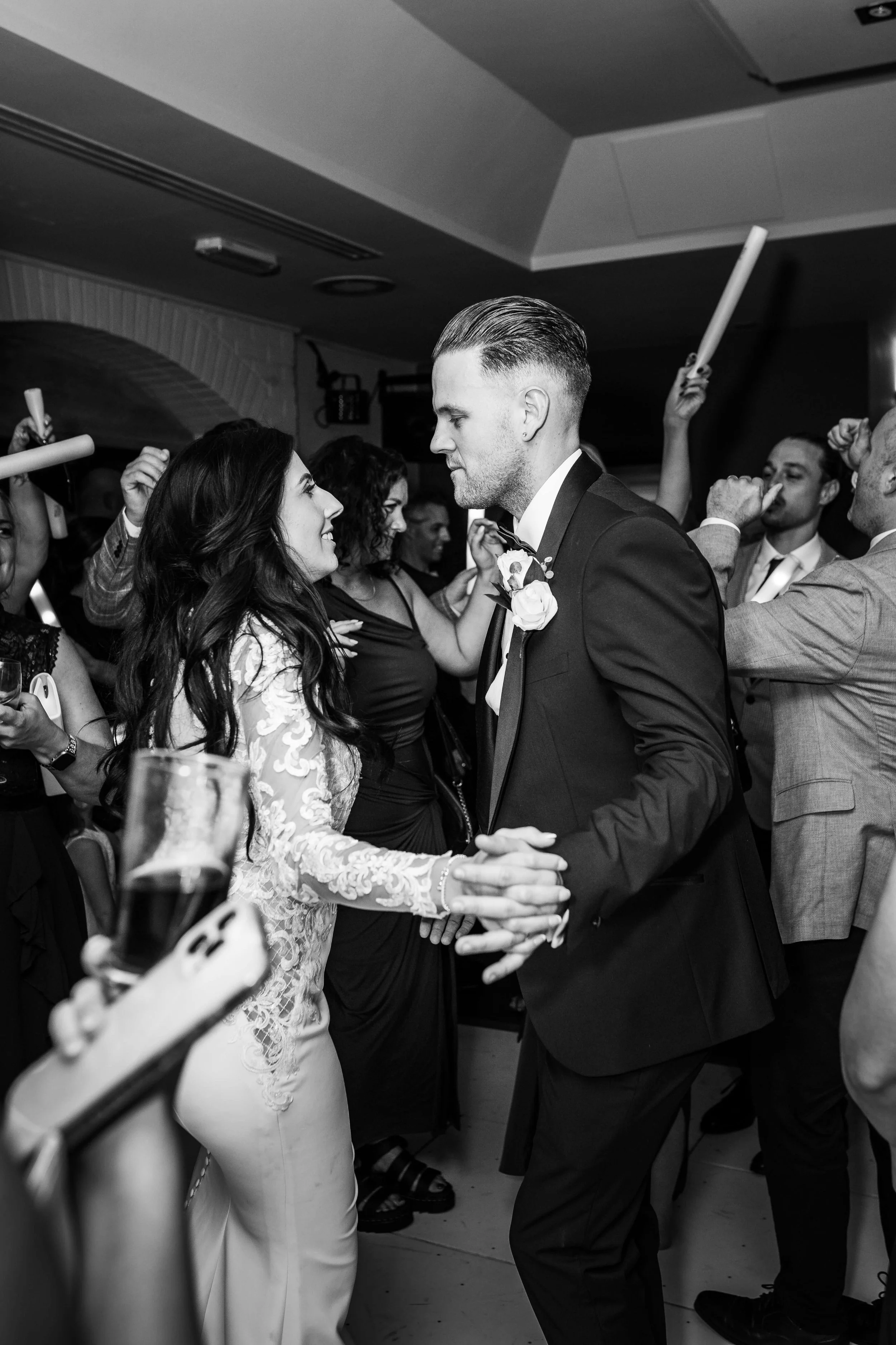 A bride and groom dancing at their wedding reception surrounded by guests in a lively atmosphere.
