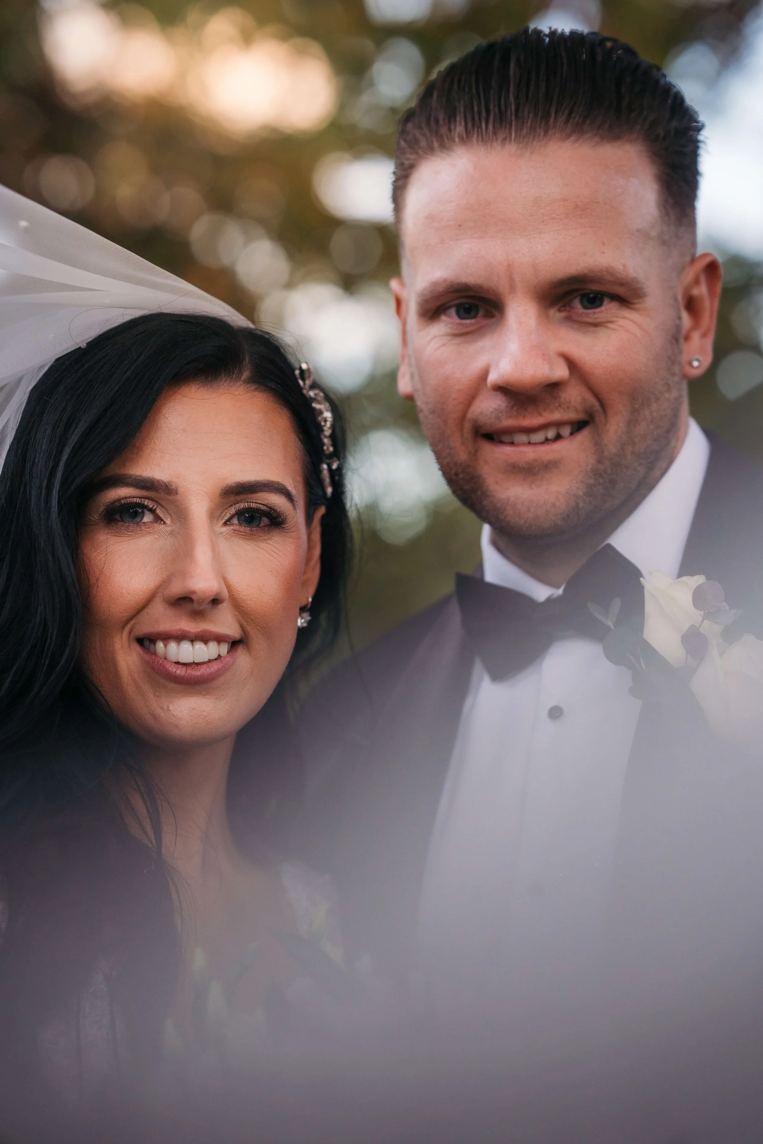 bride and groom in photo hazed by the brides veil with soft bokeh in back ground 