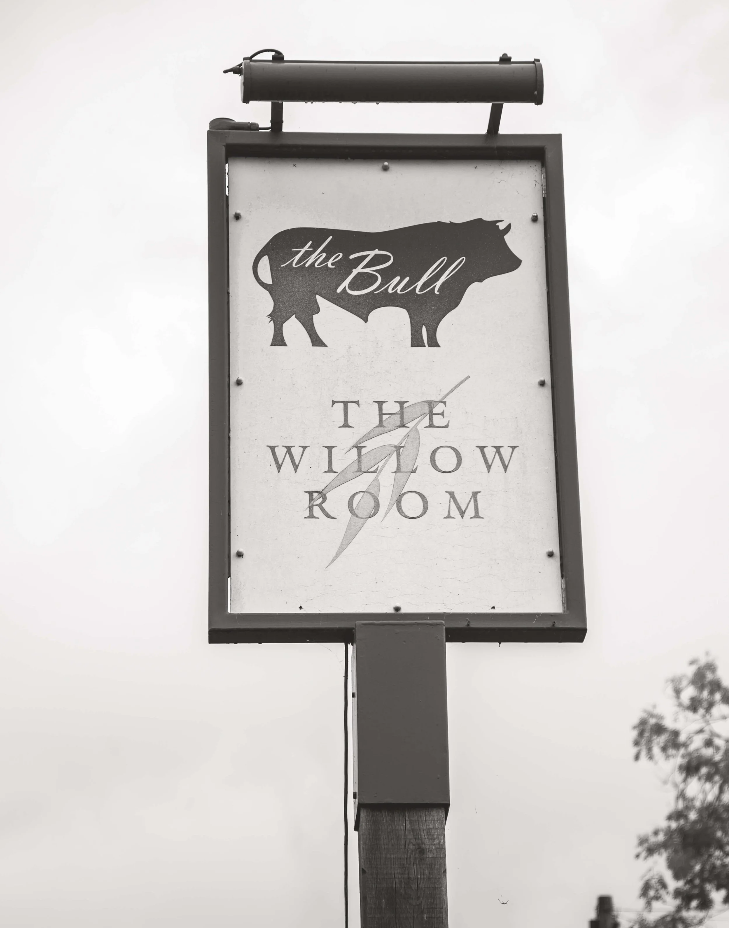 A sign with a silhouette of a bull and the words "the Bull" at the top and "The Willow Room" at the bottom, with a clock graphic showing approximately 8:20.