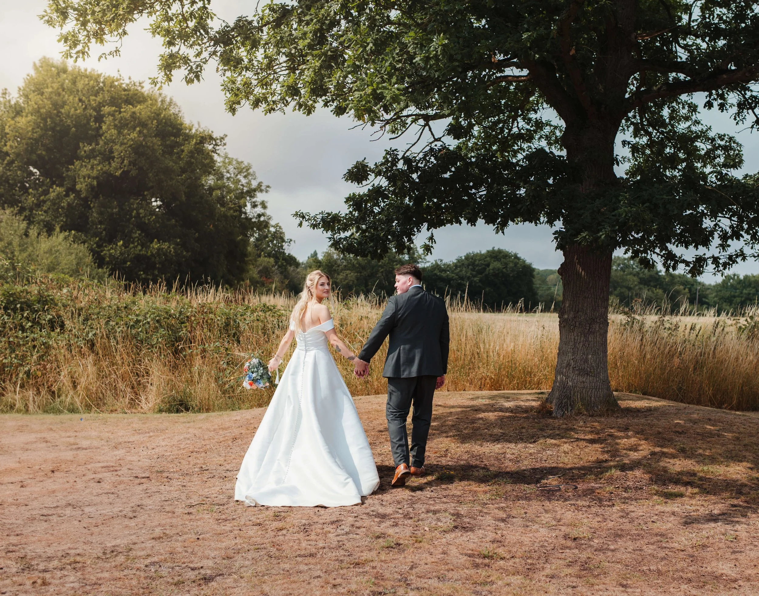 bride and groom walking away hand in hand looking over shoulder 
