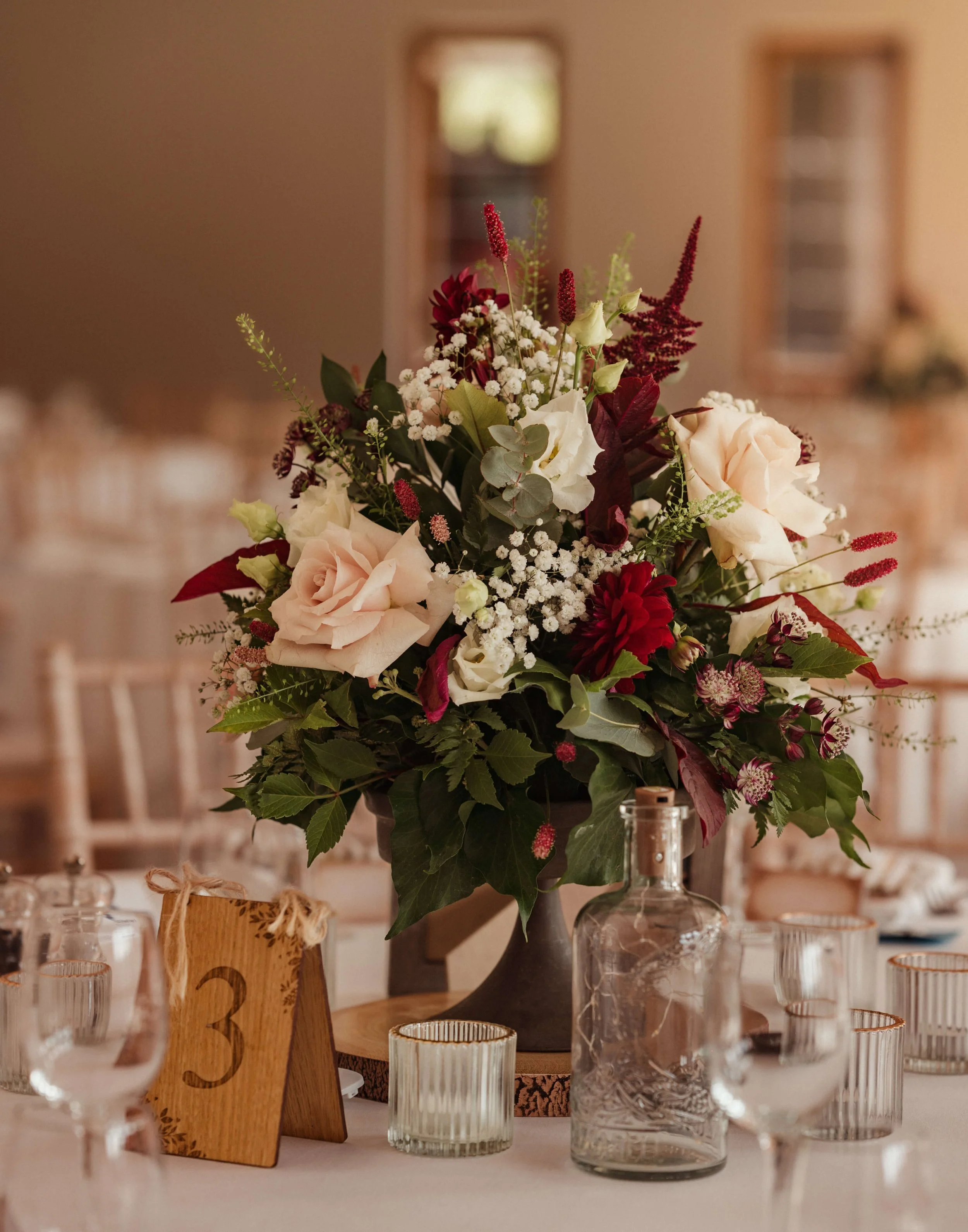Large floral centerpiece with pink and red flowers on a table at a formal event.