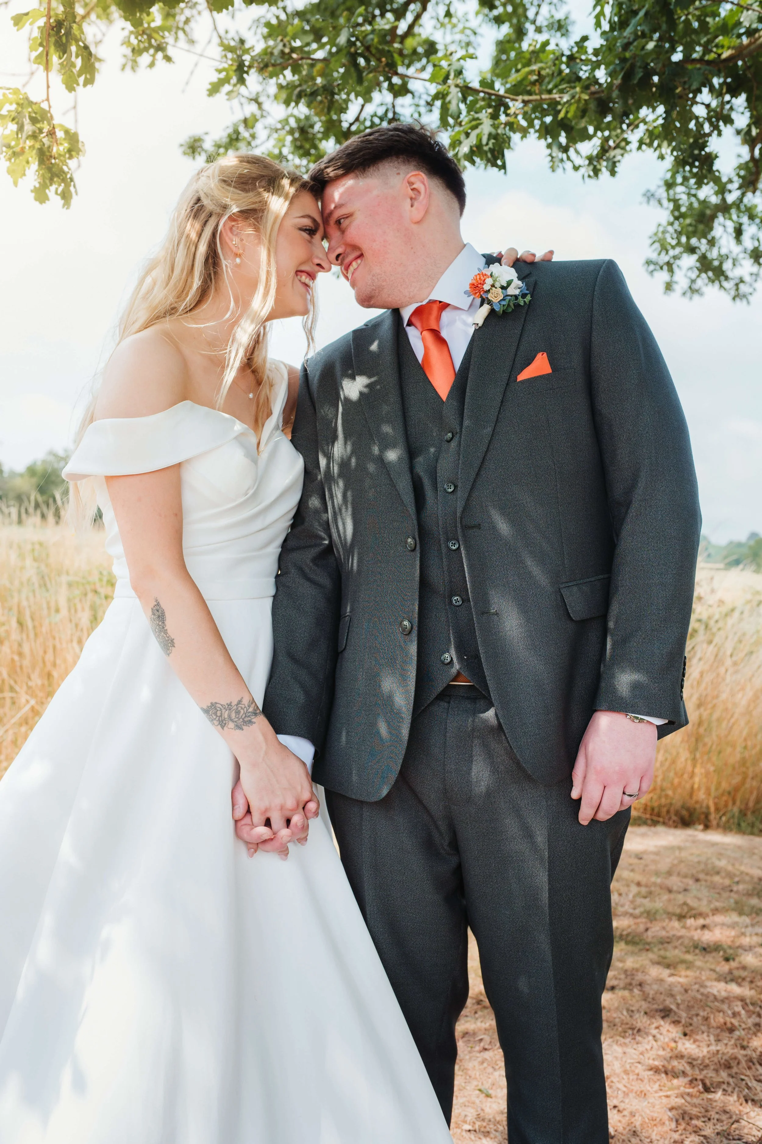 bride and groom get cosy with heads together whilst holding hands 