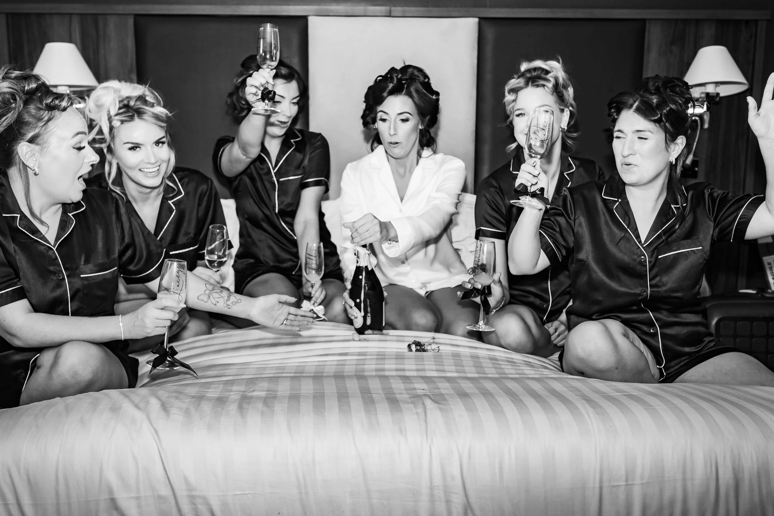 bride popping the cork with her bridesmaids in their silk robes