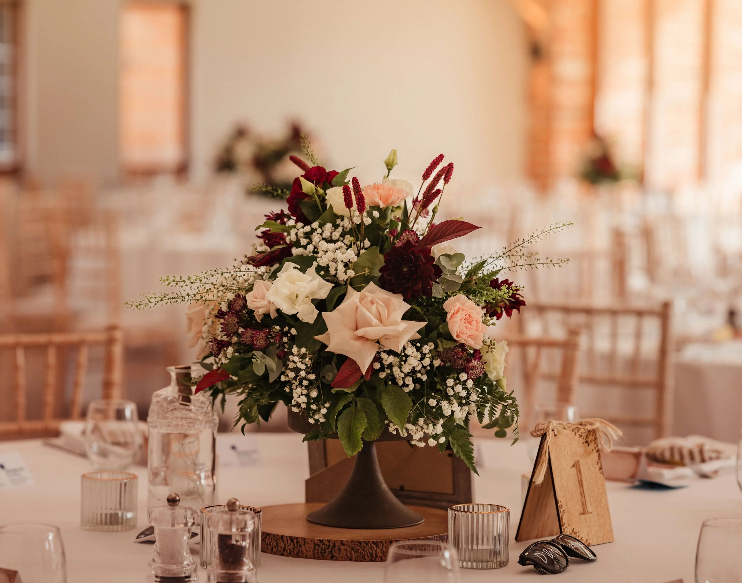 A floral centerpiece with pink, white, and red flowers on a dining table at a formal event.