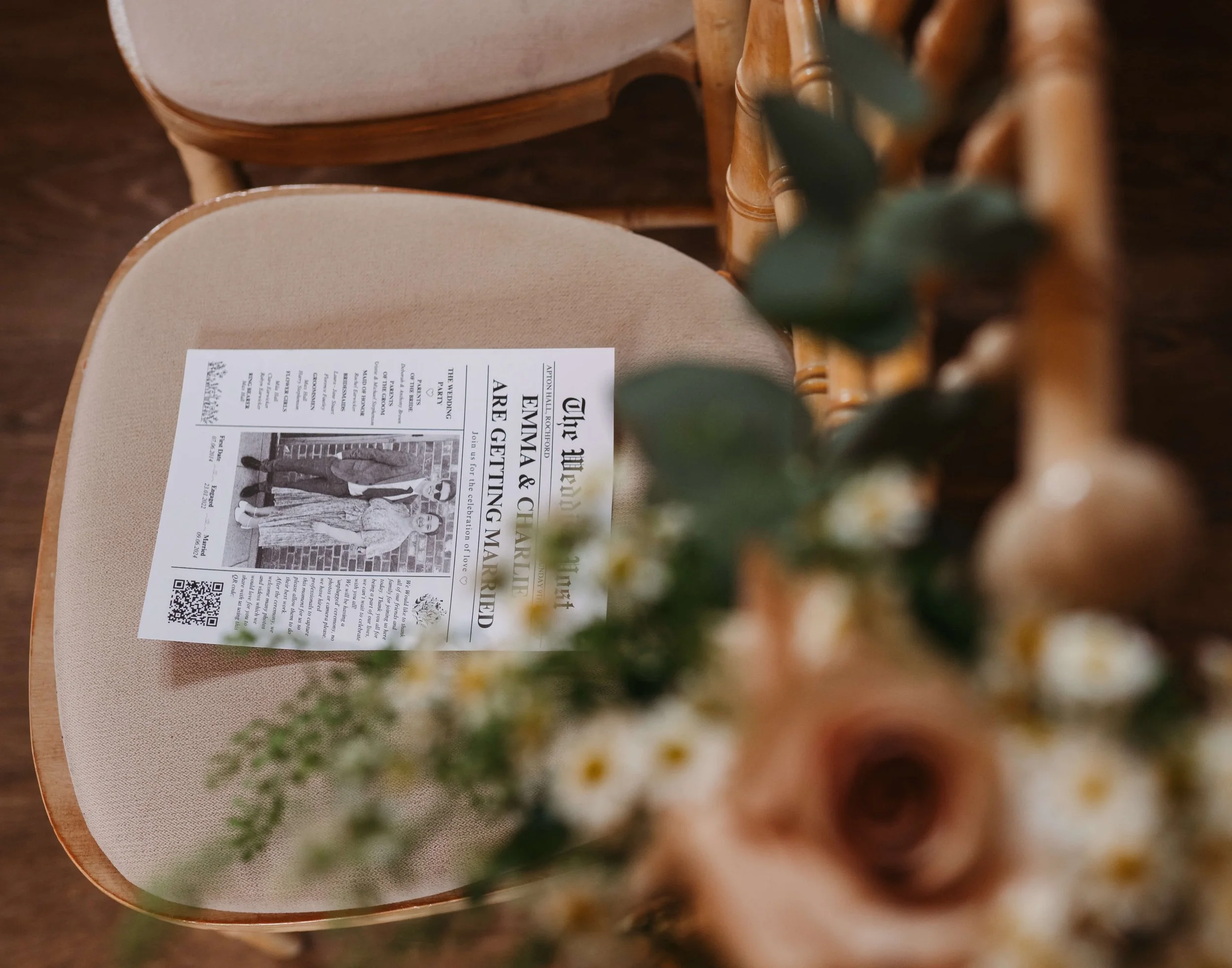 A newspaper placed on a beige chair with a flower arrangement in the foreground, partially obscuring the view.