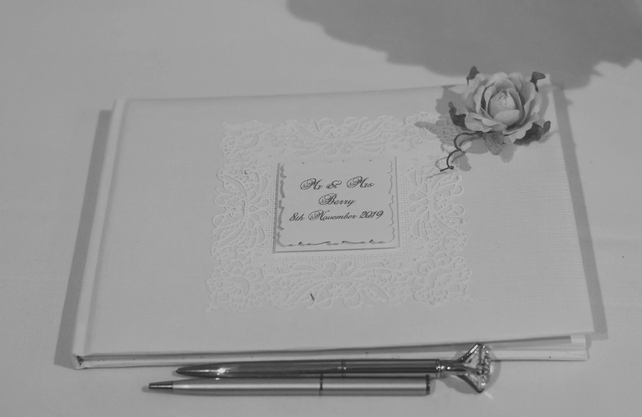 Wedding guestbook with a pen and decorative flower, inscribed with 'Mr & Mrs Berry, 8th November 2019'