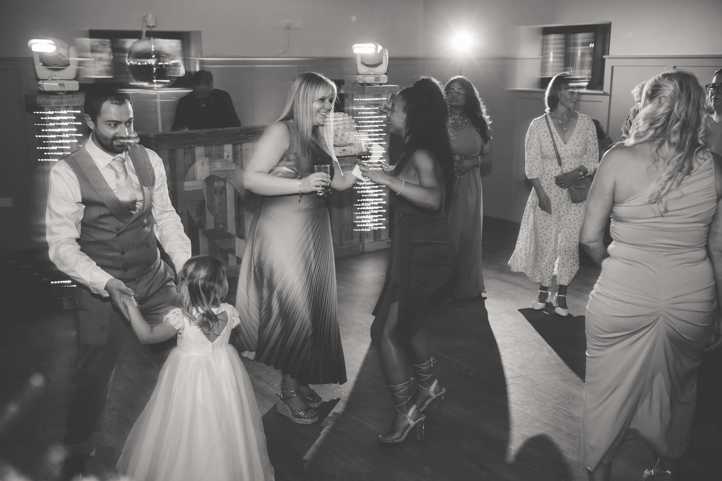 People dancing and socializing at a party with a bar in the background, black and white photo.