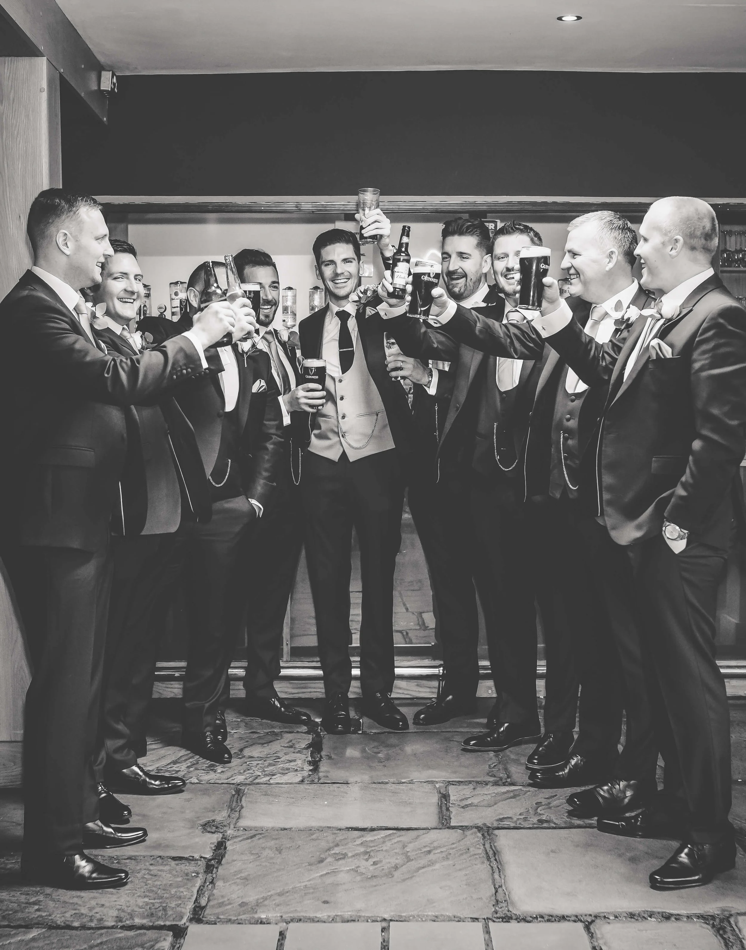 A group of men in tuxedos raising glasses in a toast at a celebration or gathering.