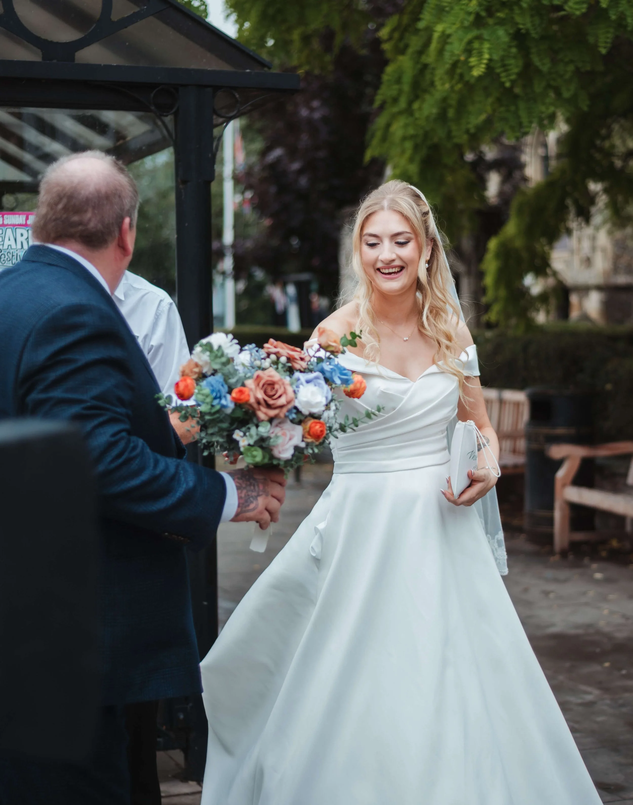 father handing bride her bouquet as she steps out of her vw beetle open top car