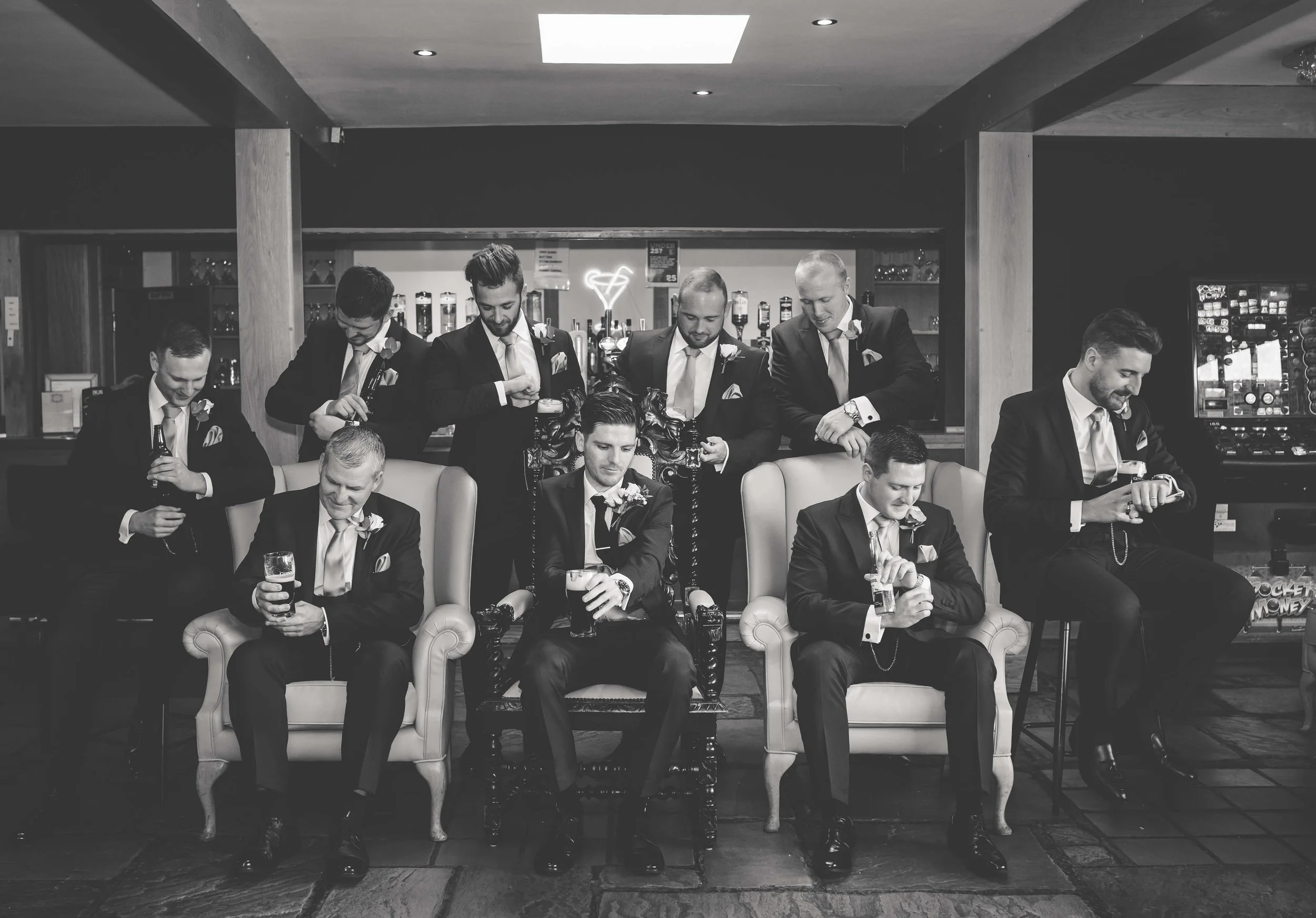 groomsmen all check their watches and cufflinks in editorial black and white posed photograph