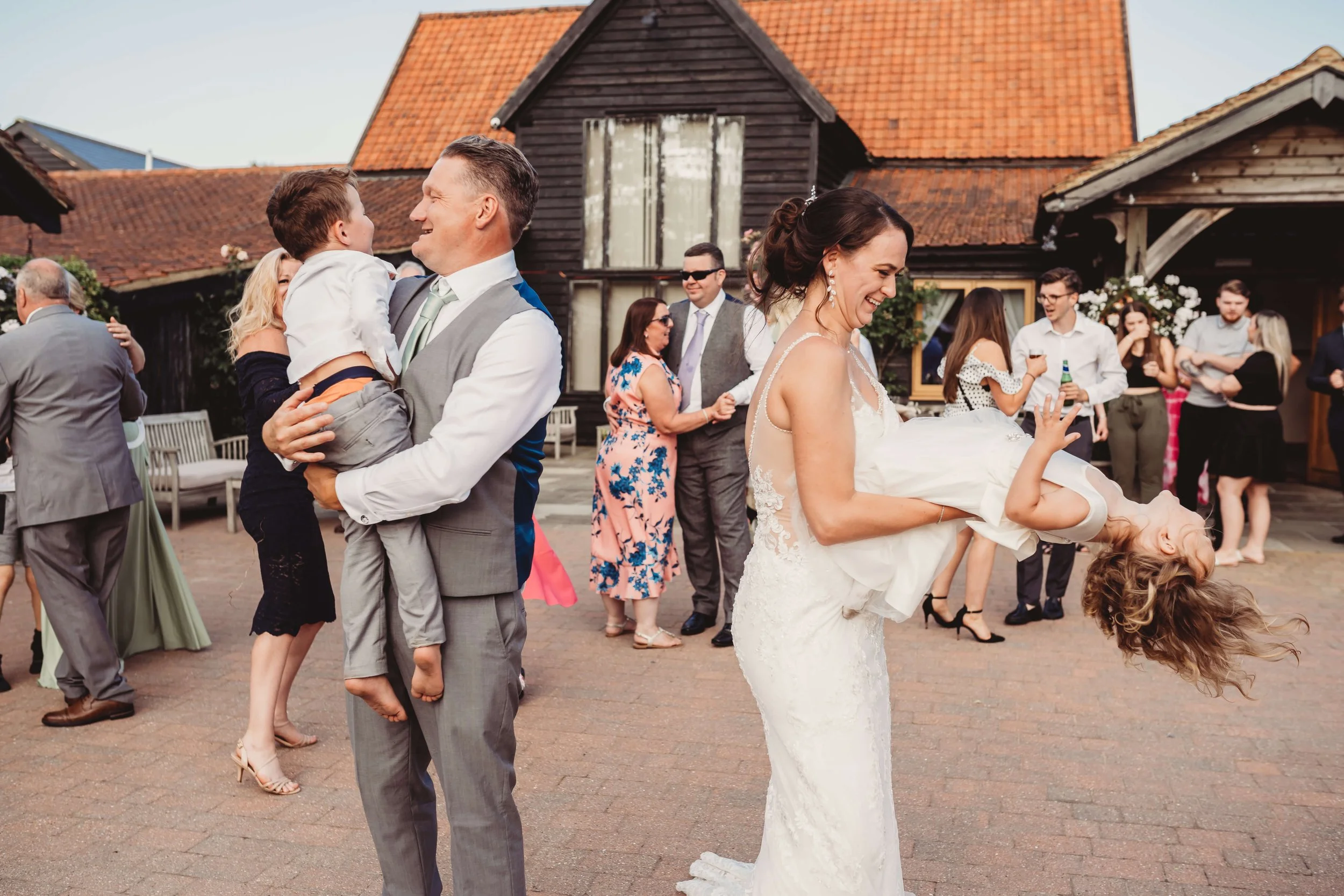 Wedding celebration with guests dancing and children playing outdoors.