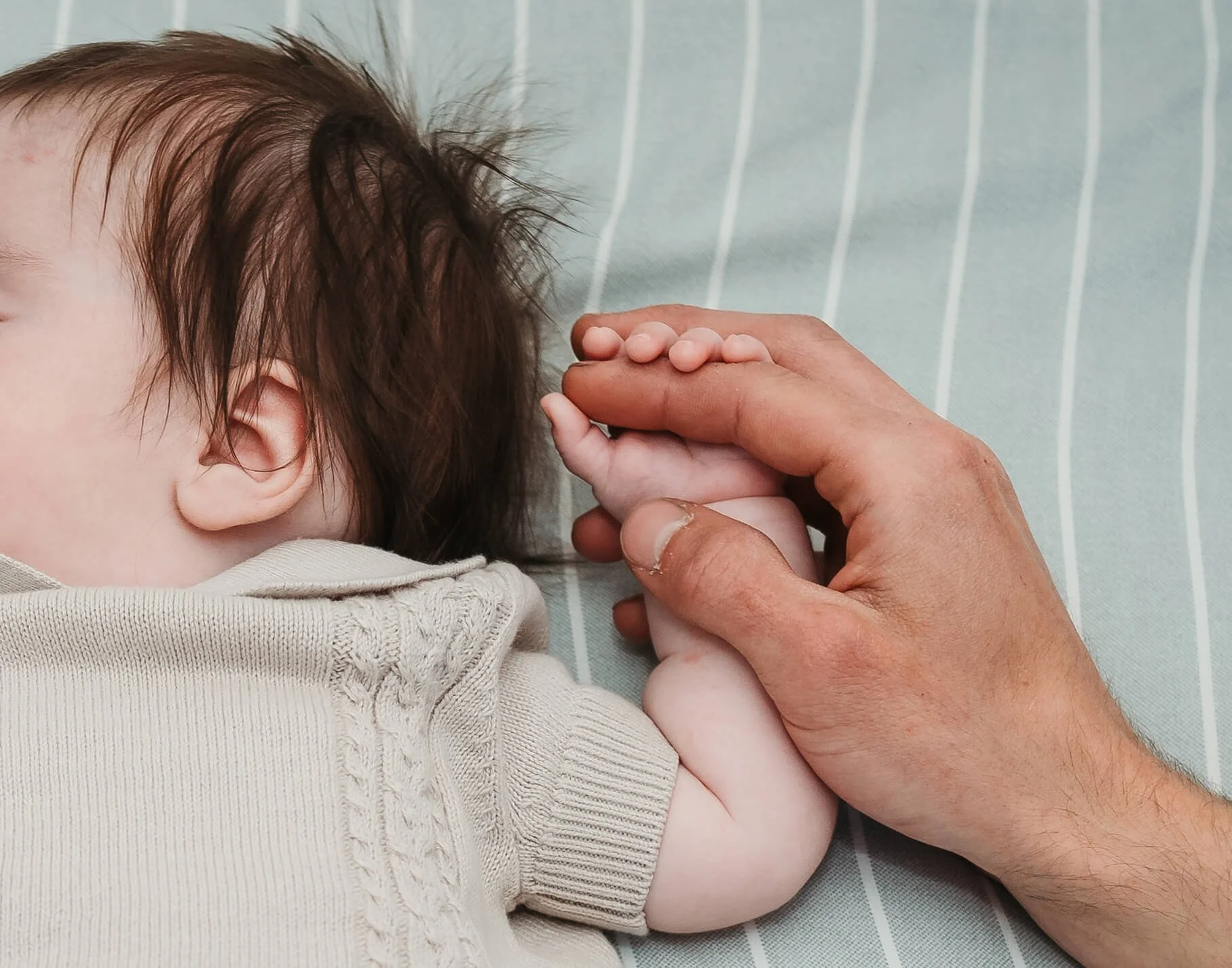 dad holding babies hand 