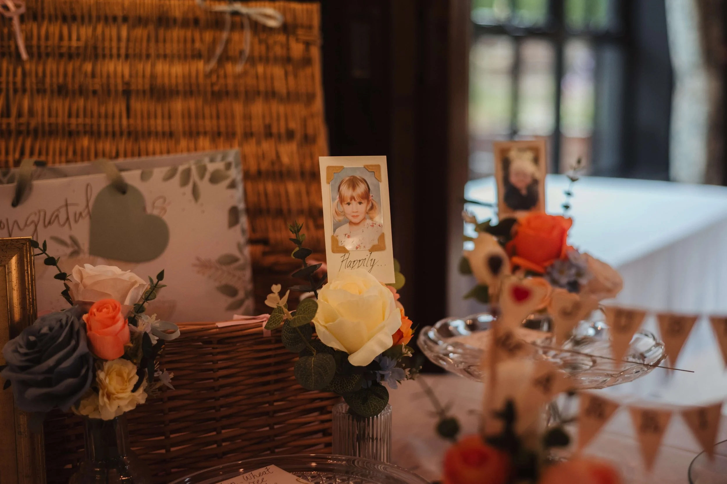 Decorative table setup with photos of children, flowers, and greeting cards, likely for a celebration or memorial event.