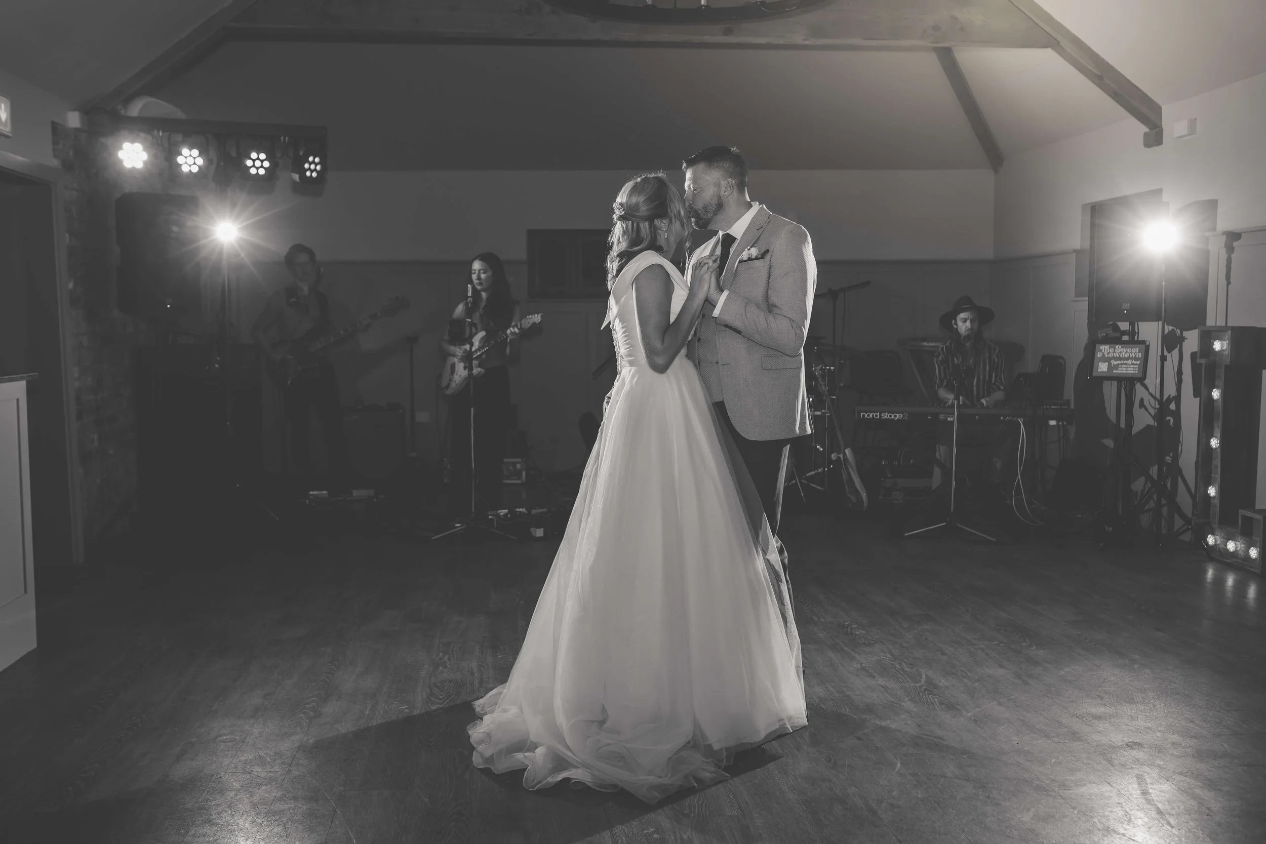 A bride and groom sharing a dance at their wedding reception with live band playing in the background.