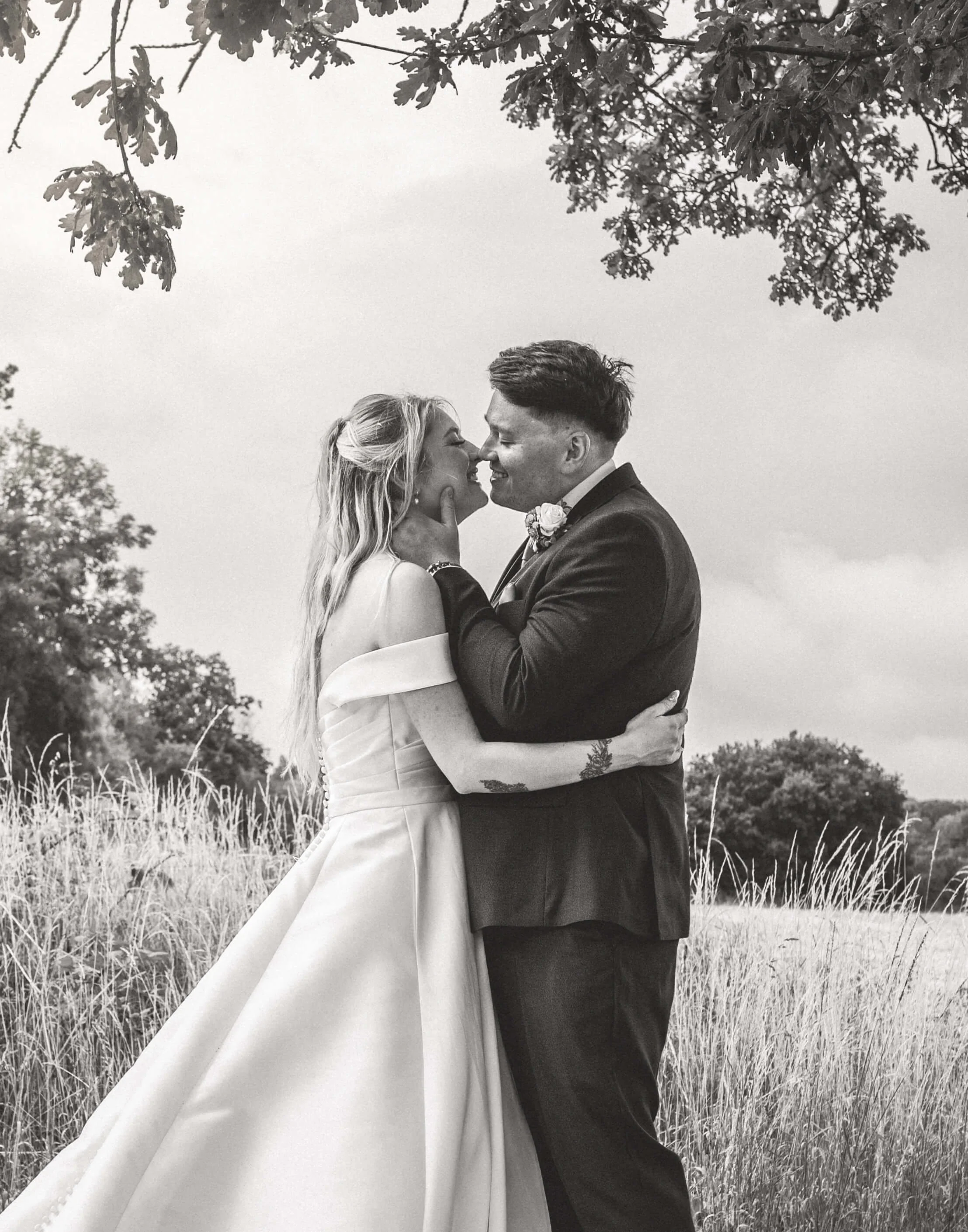black and white romantic shot of groom gently holding brides chin before embace