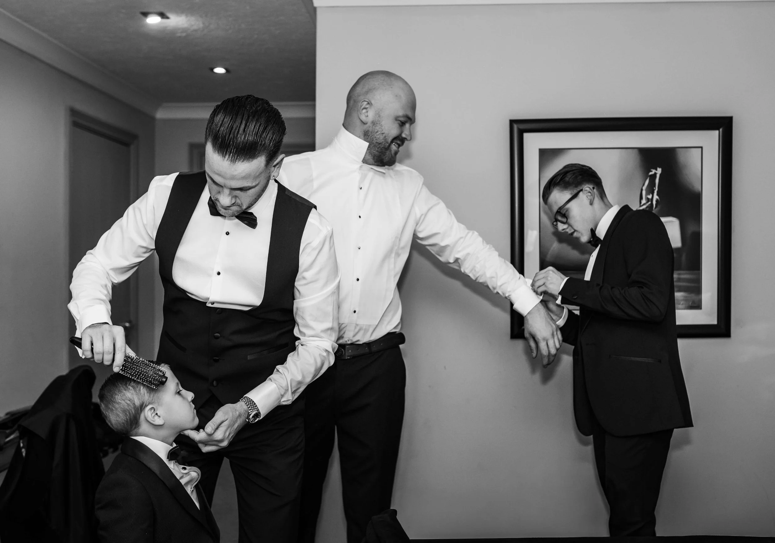 Grooms getting ready togethercombing hair and helping with cufflinks 