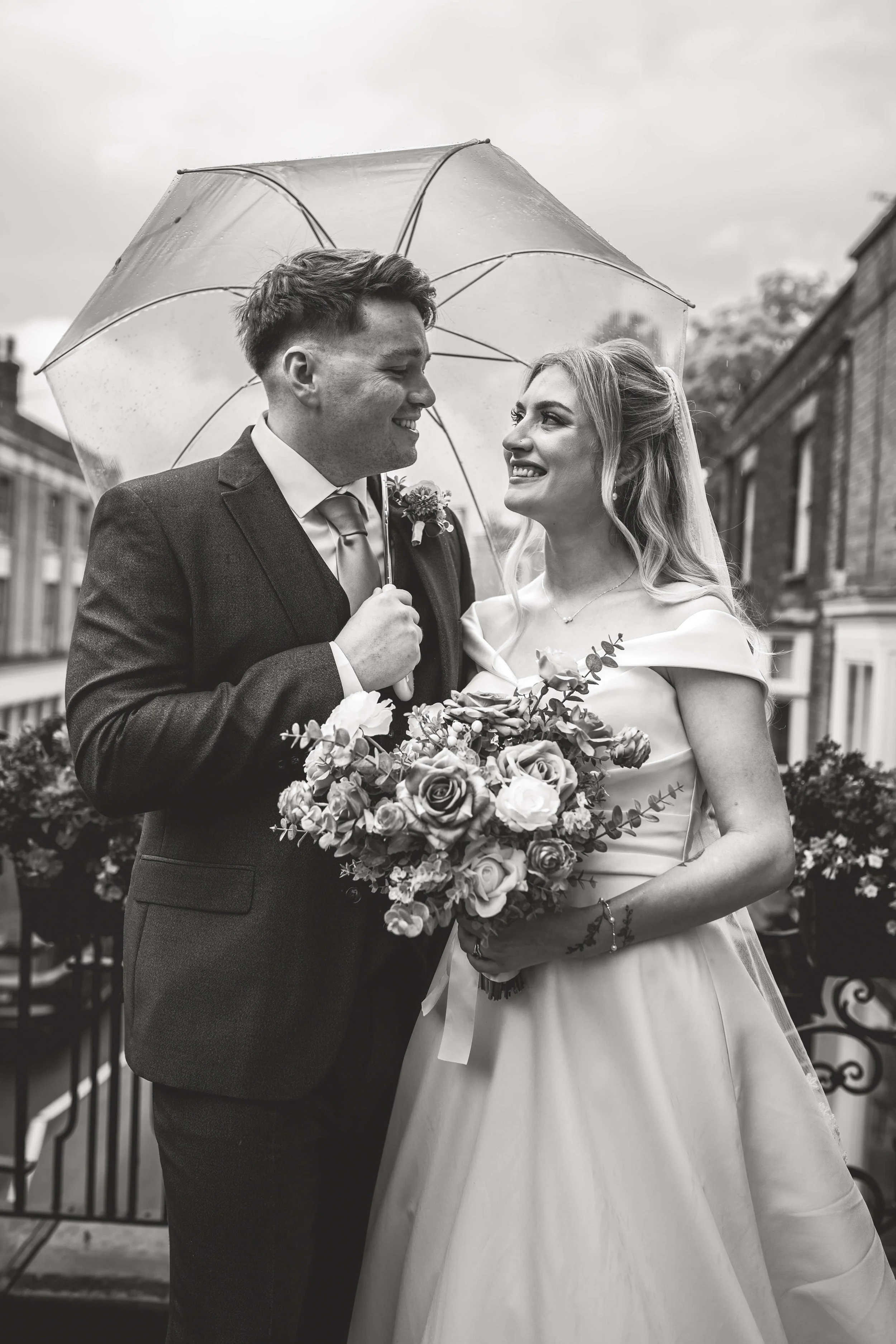 bride and groom staring lovingly into each others eyes under an umbrella on the balcony of their ceremony