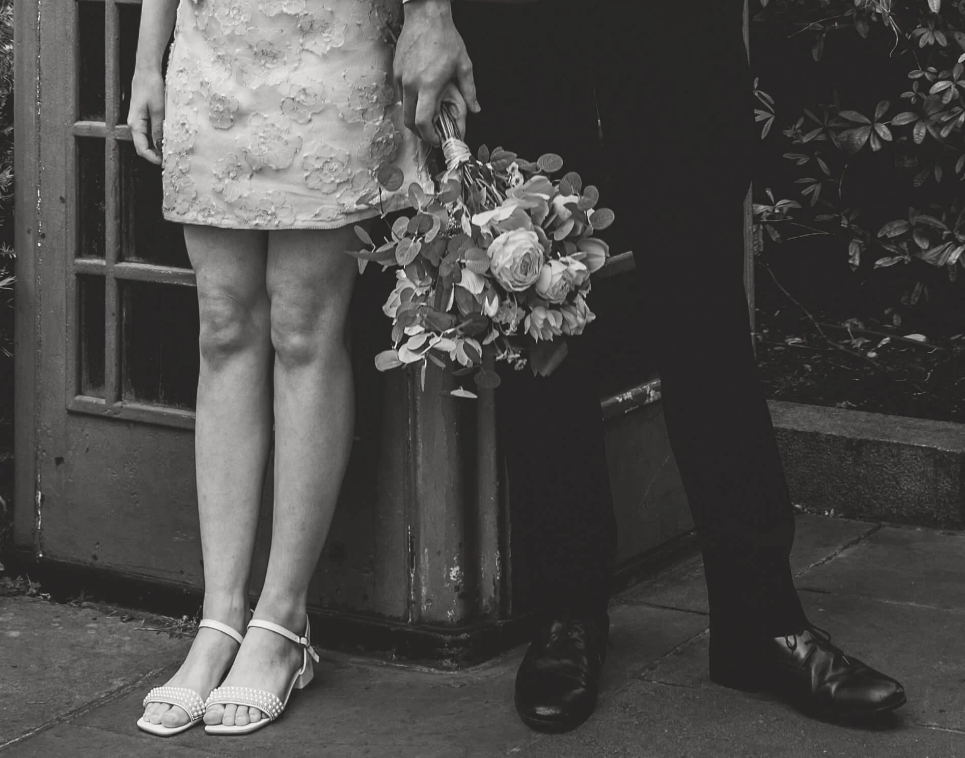 black and white photo of bride and groom feet and bouquet