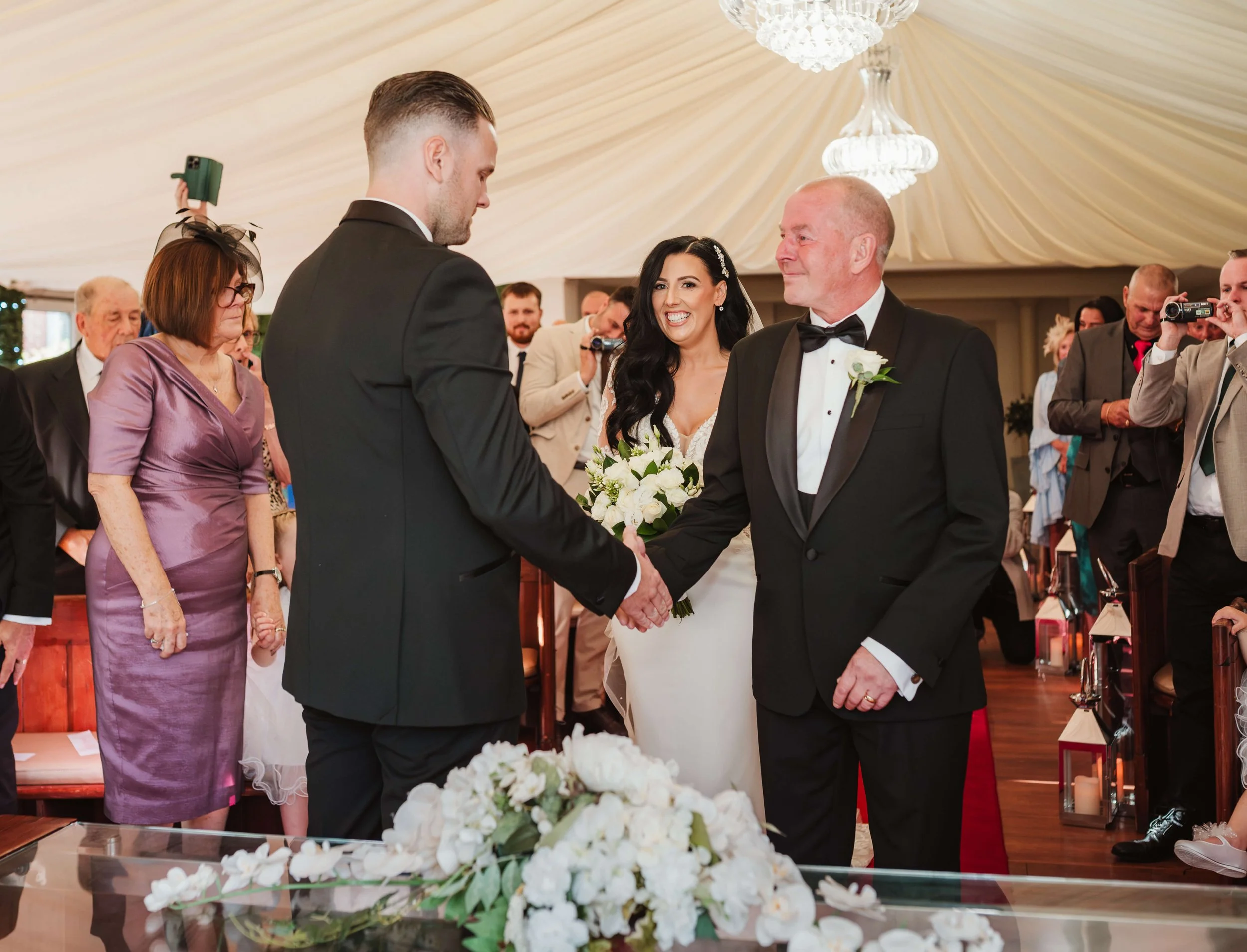 groom and father of the bride shaking hands whilst giving his daughter away