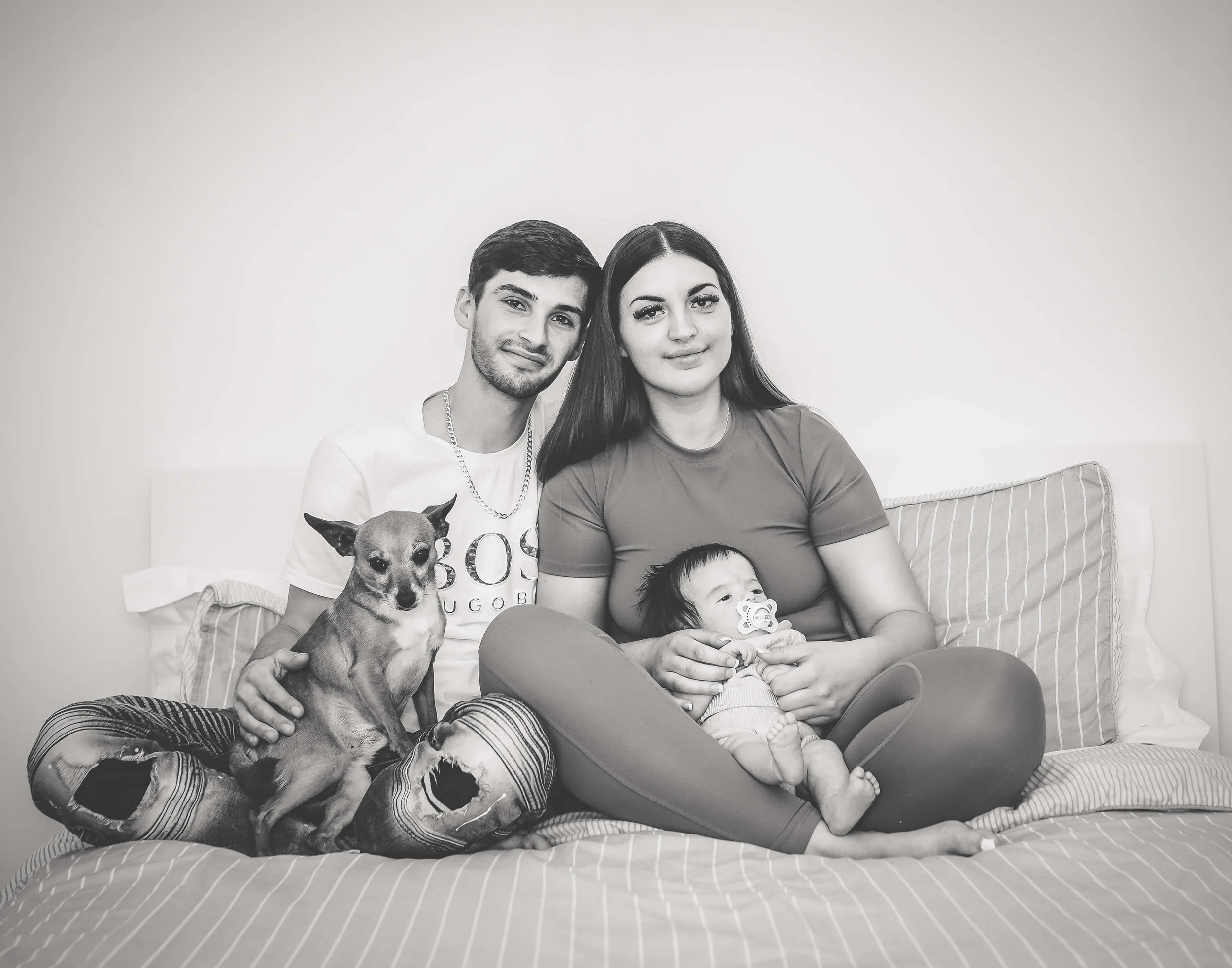 mum and dad on bed with their baby and their pet dog in this lifestyle shot 