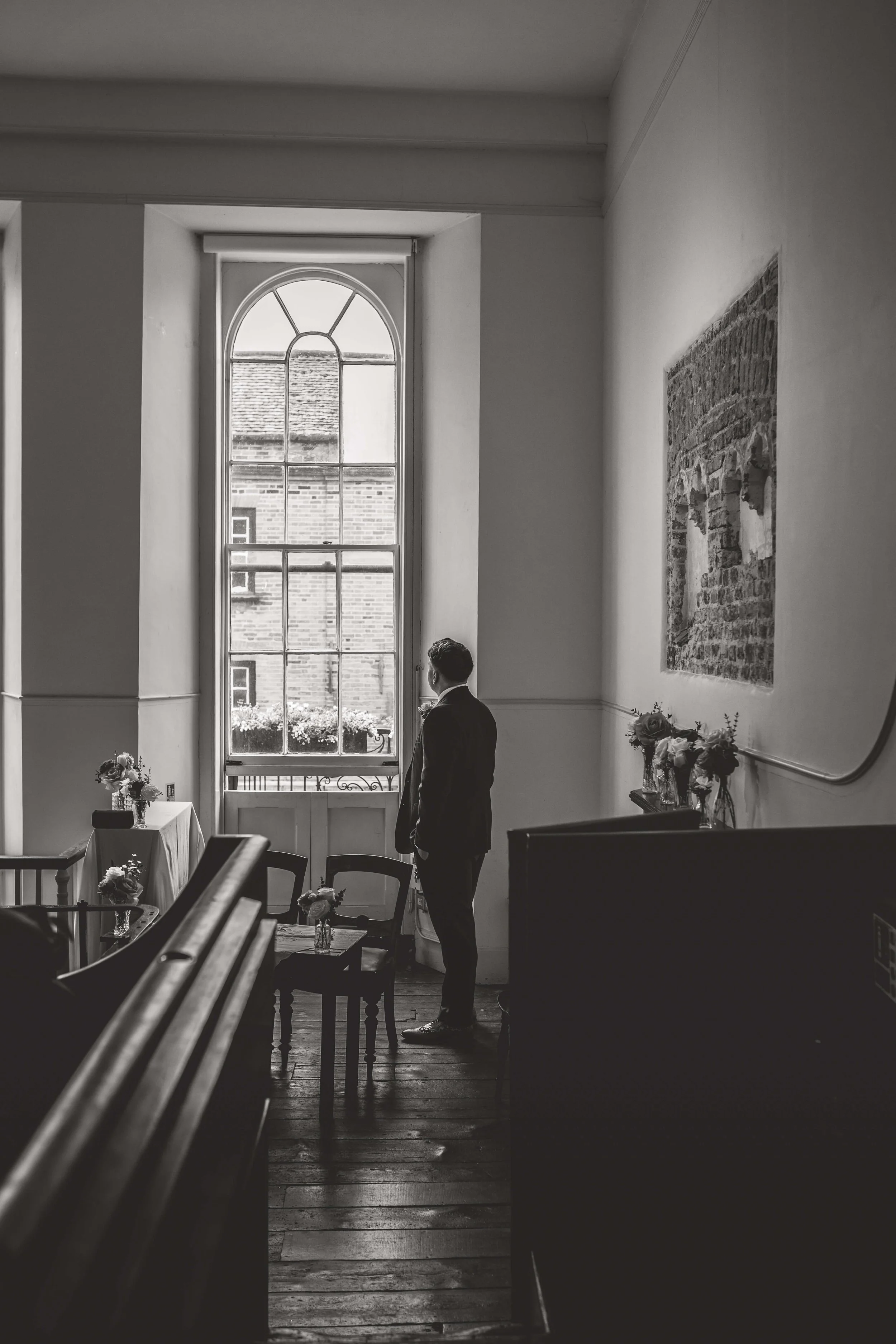 groom gazing wistfully out of window before ceremony 