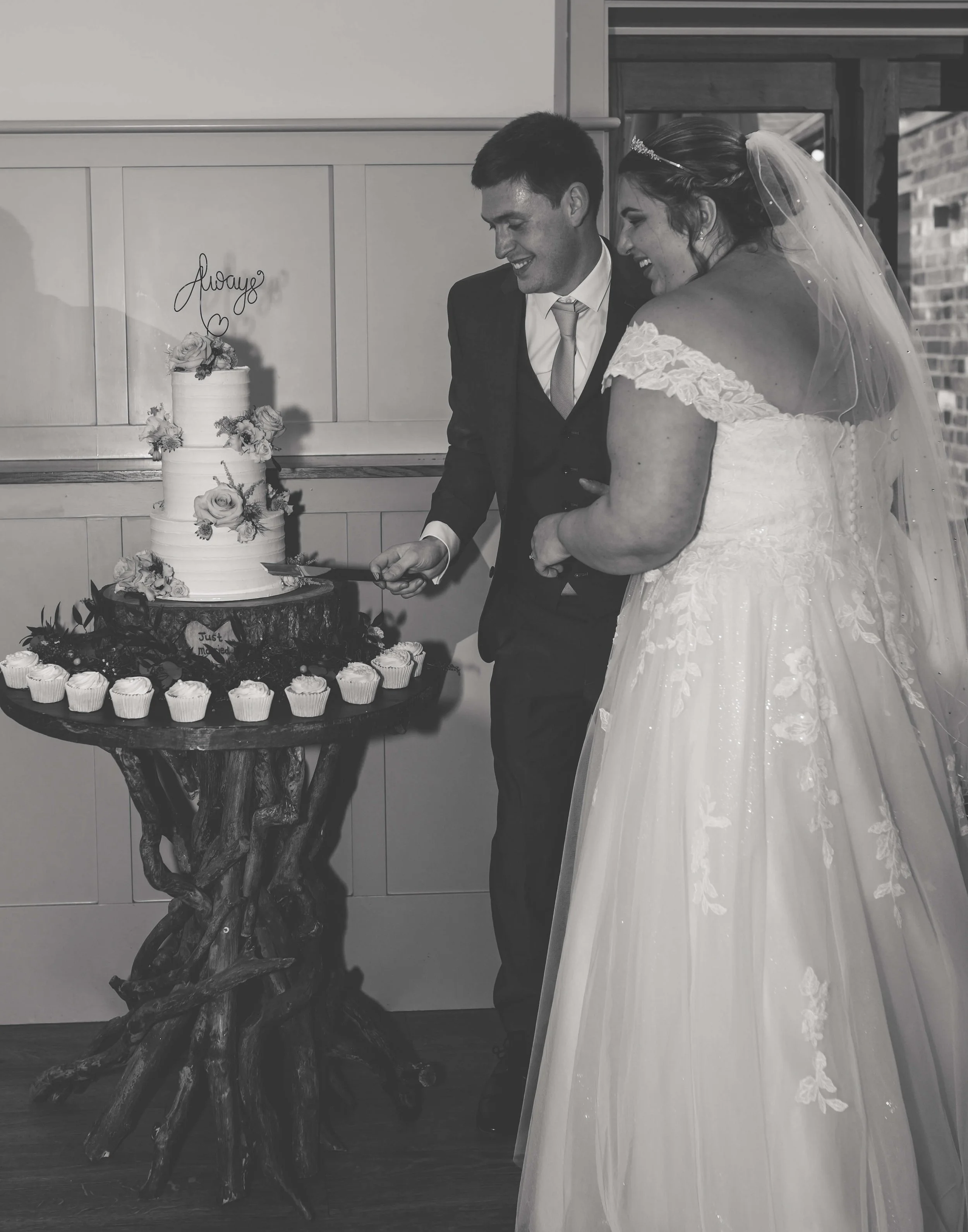 A bride and groom cut their wedding cake together at a wedding reception.