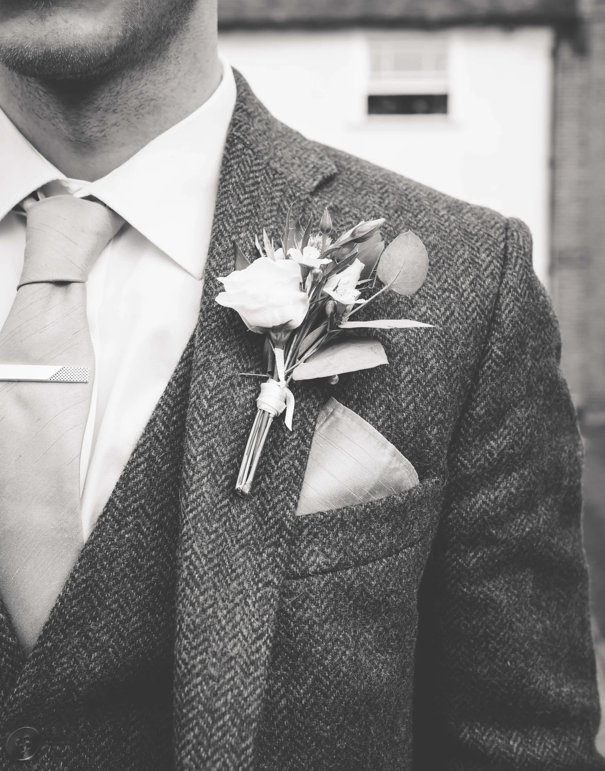 Close-up of a man wearing a suit, with a boutonniere pinned to his jacket lapel.