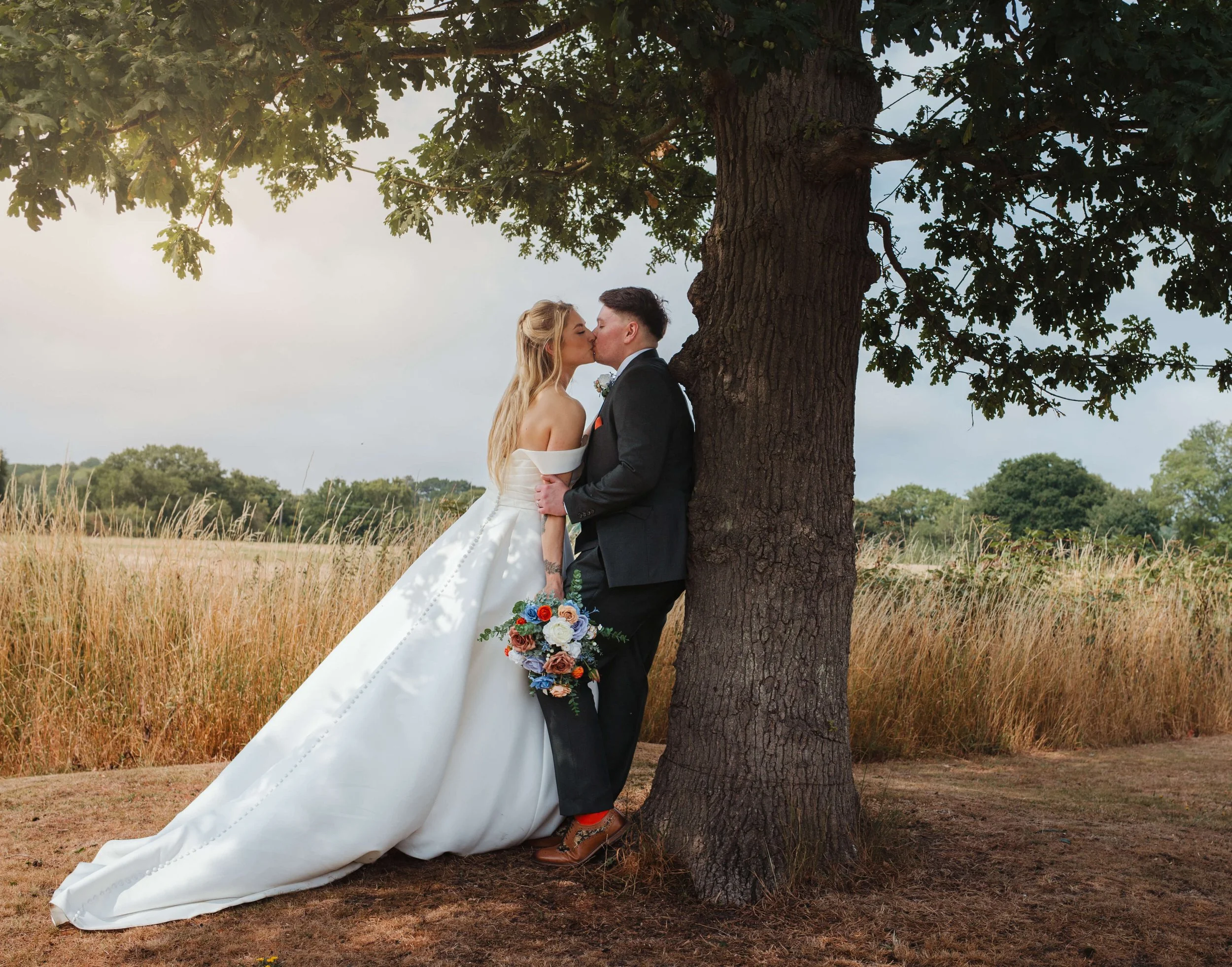 bride and groom kiss in beautiful photograph together under the tree 