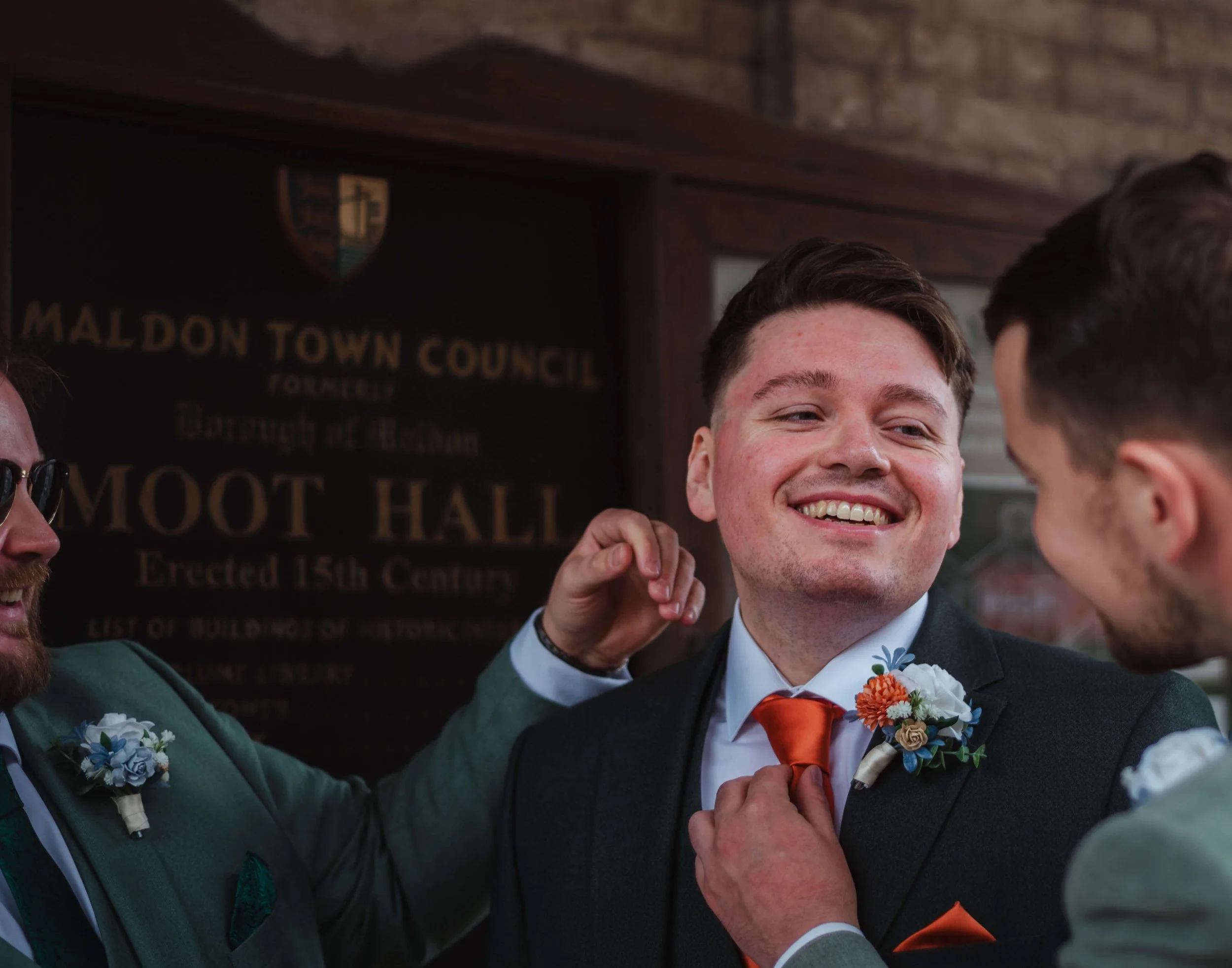 groomsmen rearranging brides tie outside wedding venue