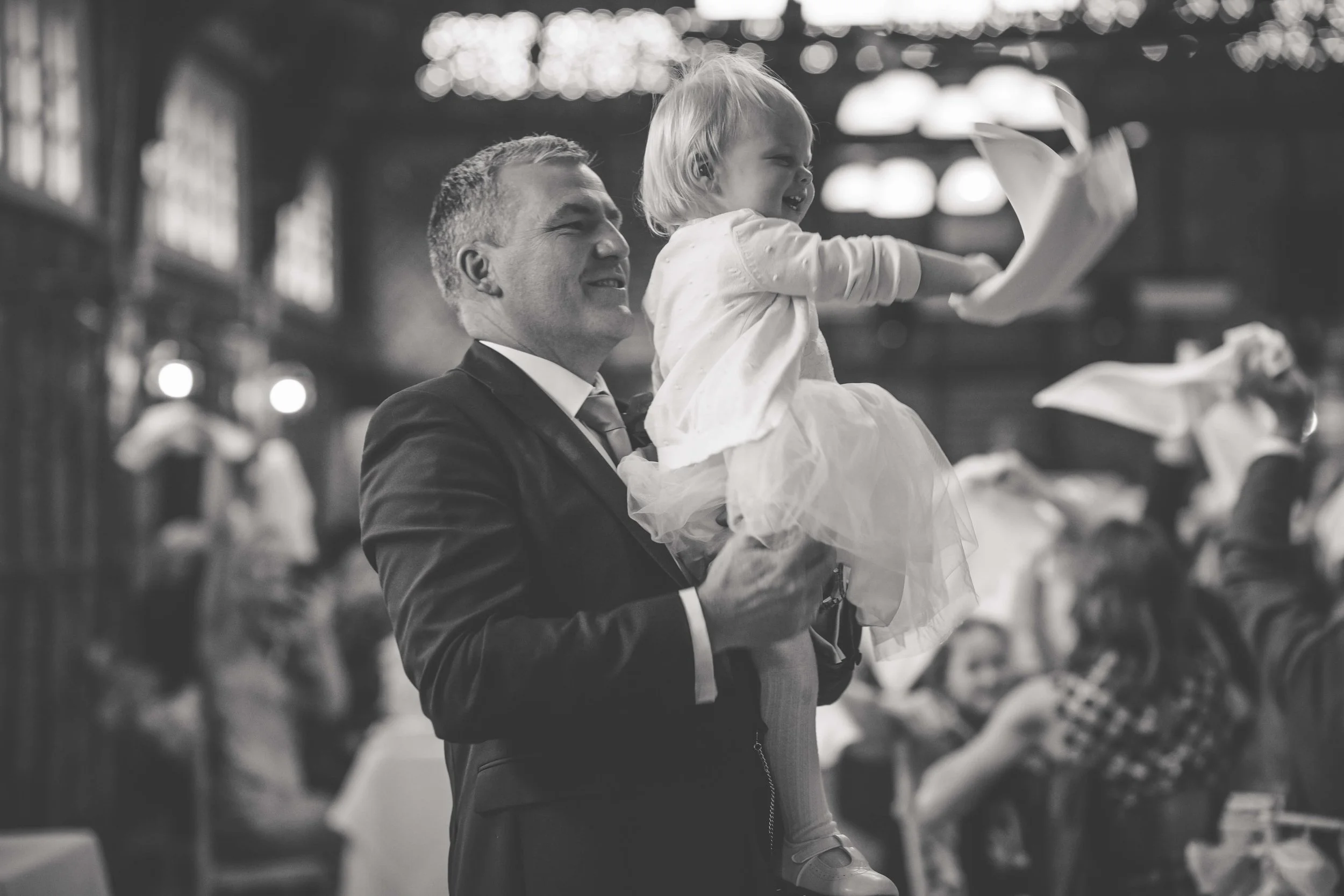 man holding bridesmaid flower girl as she waves hanky to the music of wedding entertainer