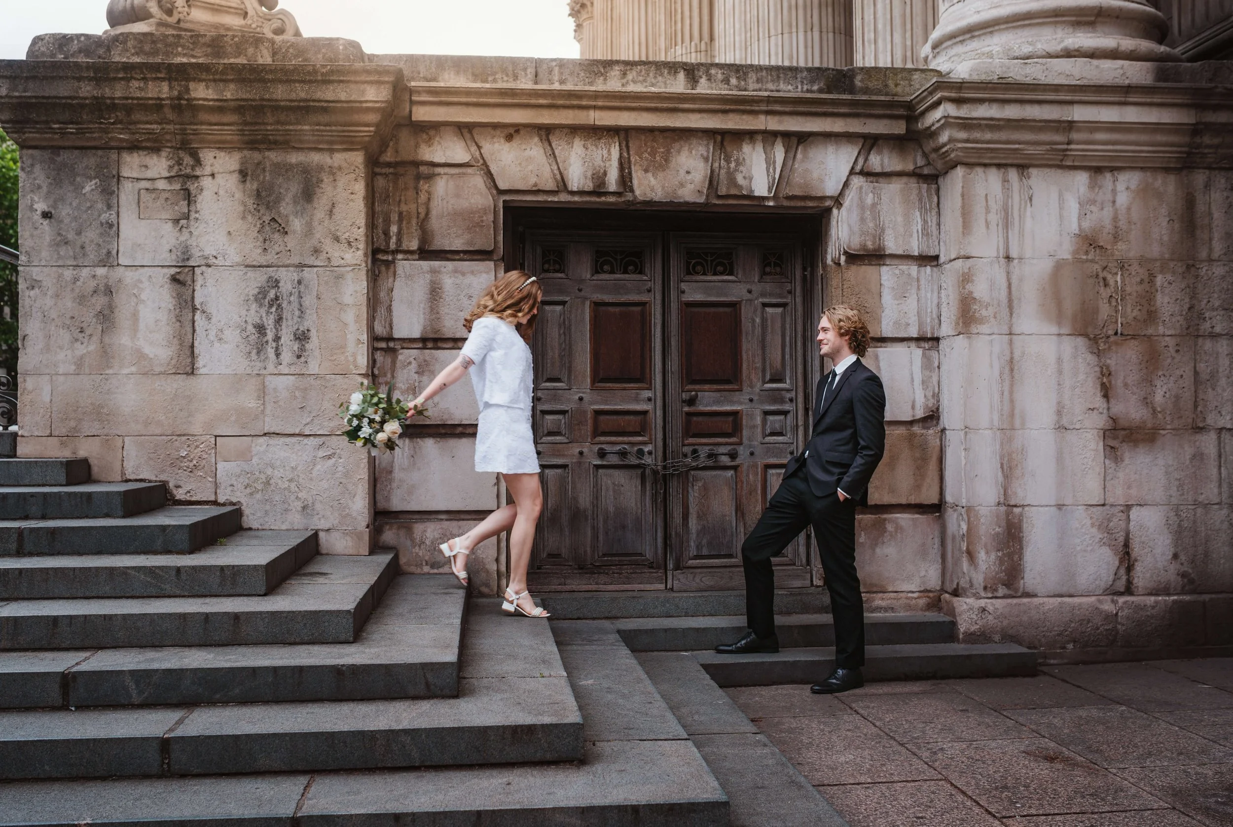 bride running down steps near St Pauls Cathedral in London to her groom in an elopement wedding