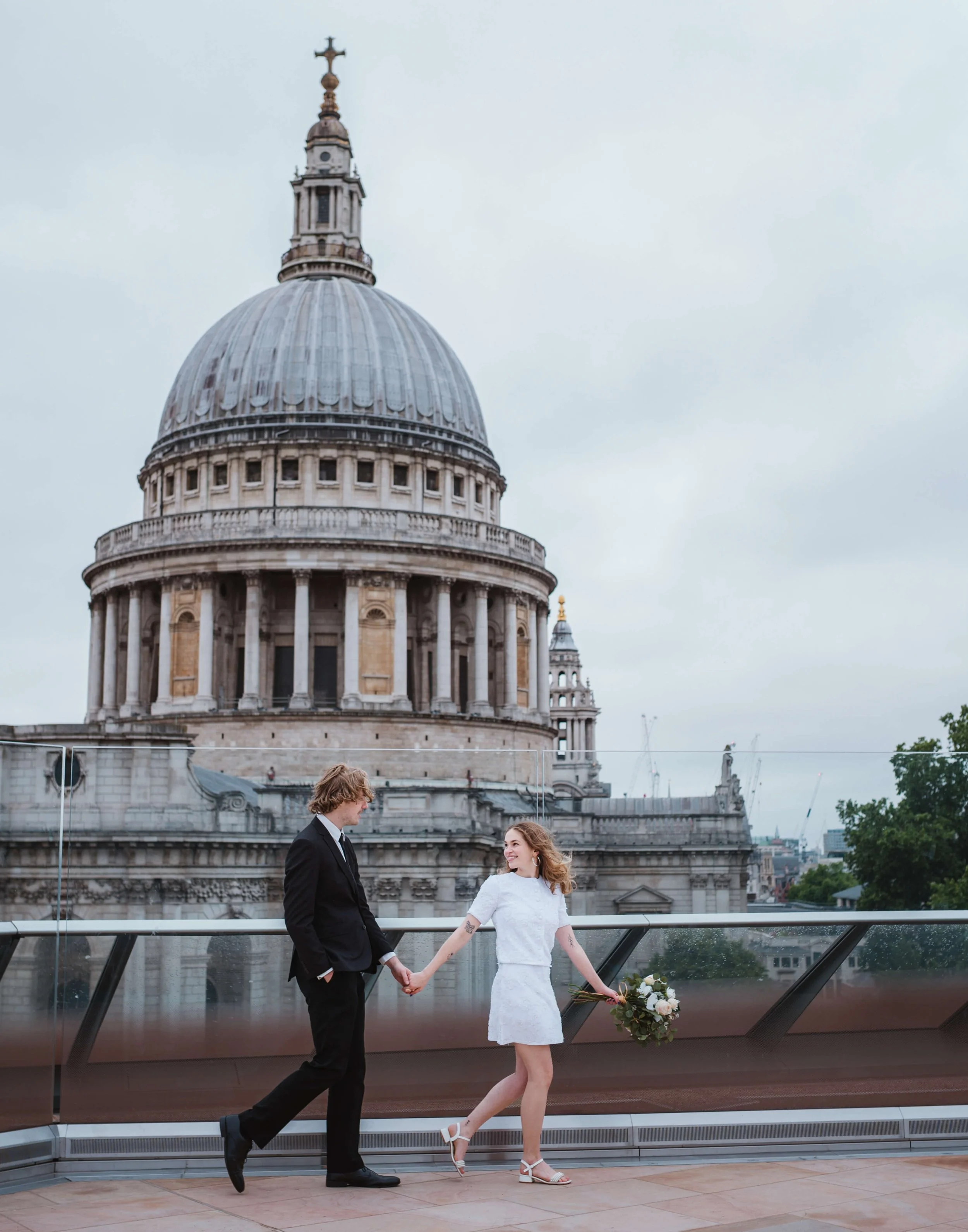 bride leads groom on rooftop of one new change opposite St Pauls Cathedral 