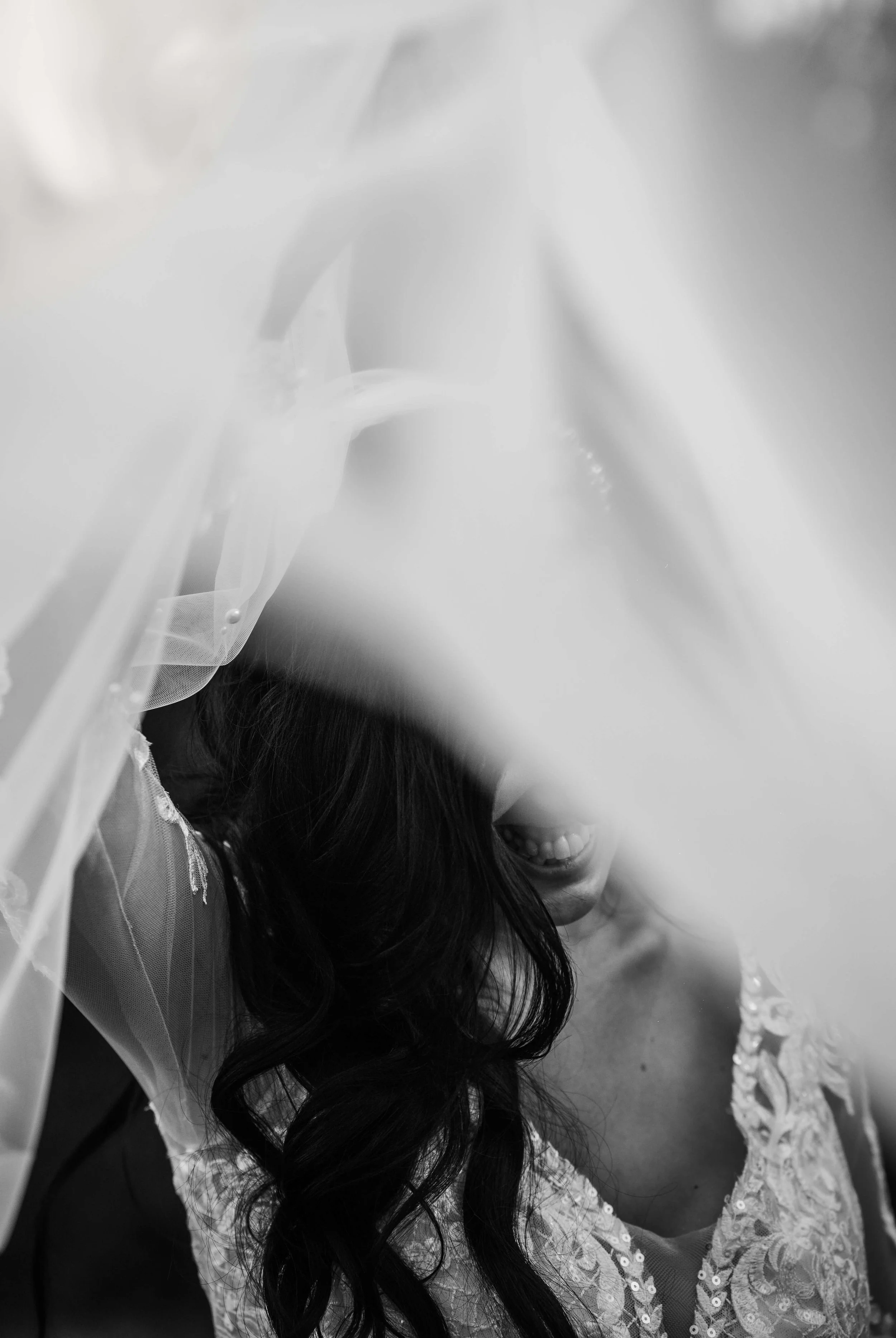 shot of bride under her veil laughing 
